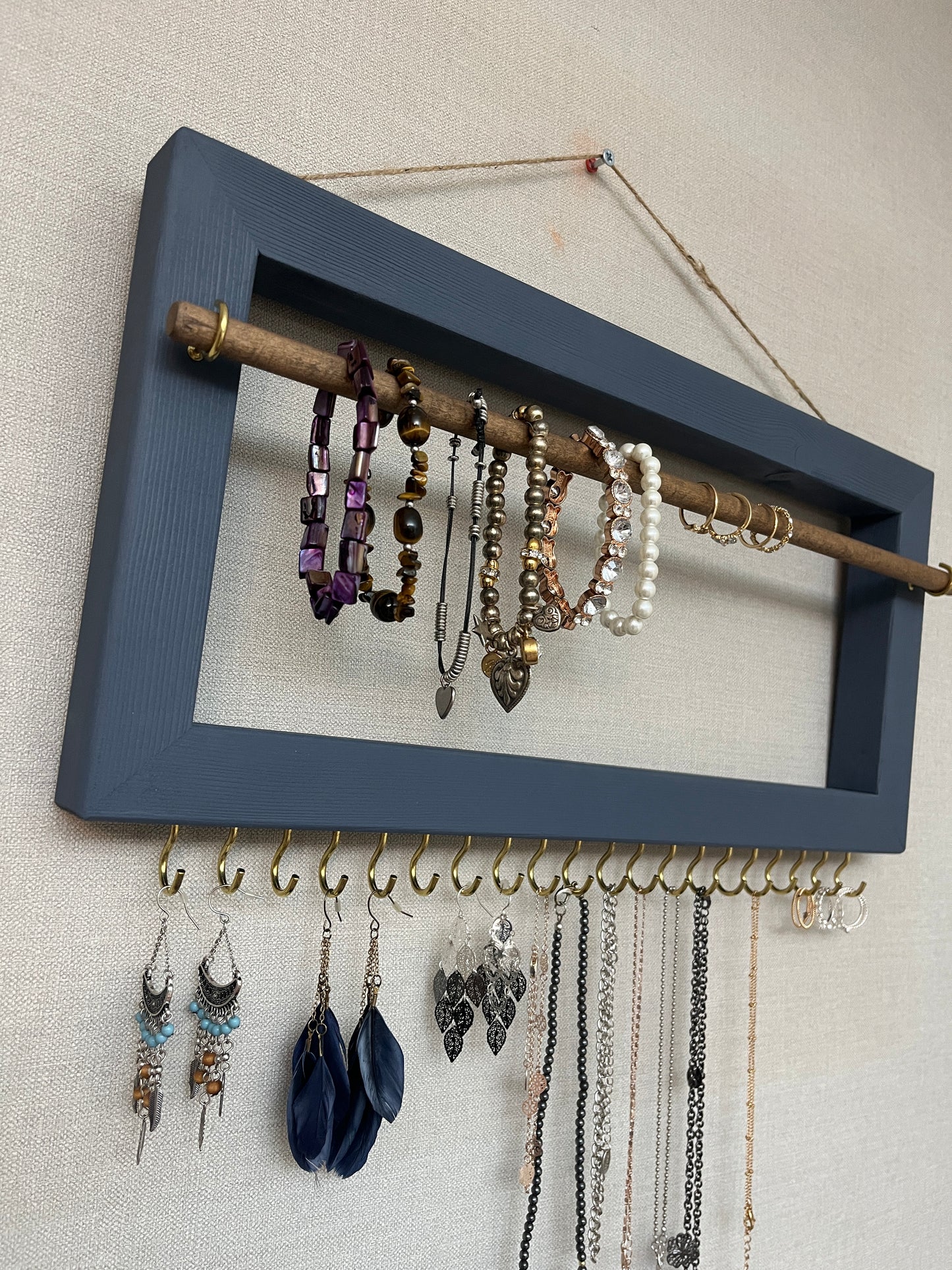 Handmade premium jewellery organizer crafted from timber, with hooks and a storage rod to safely store rings, necklaces, earrings, and bracelets. Available in 3 sizes. Frame design for wall mounting with D rings. Customizable color.