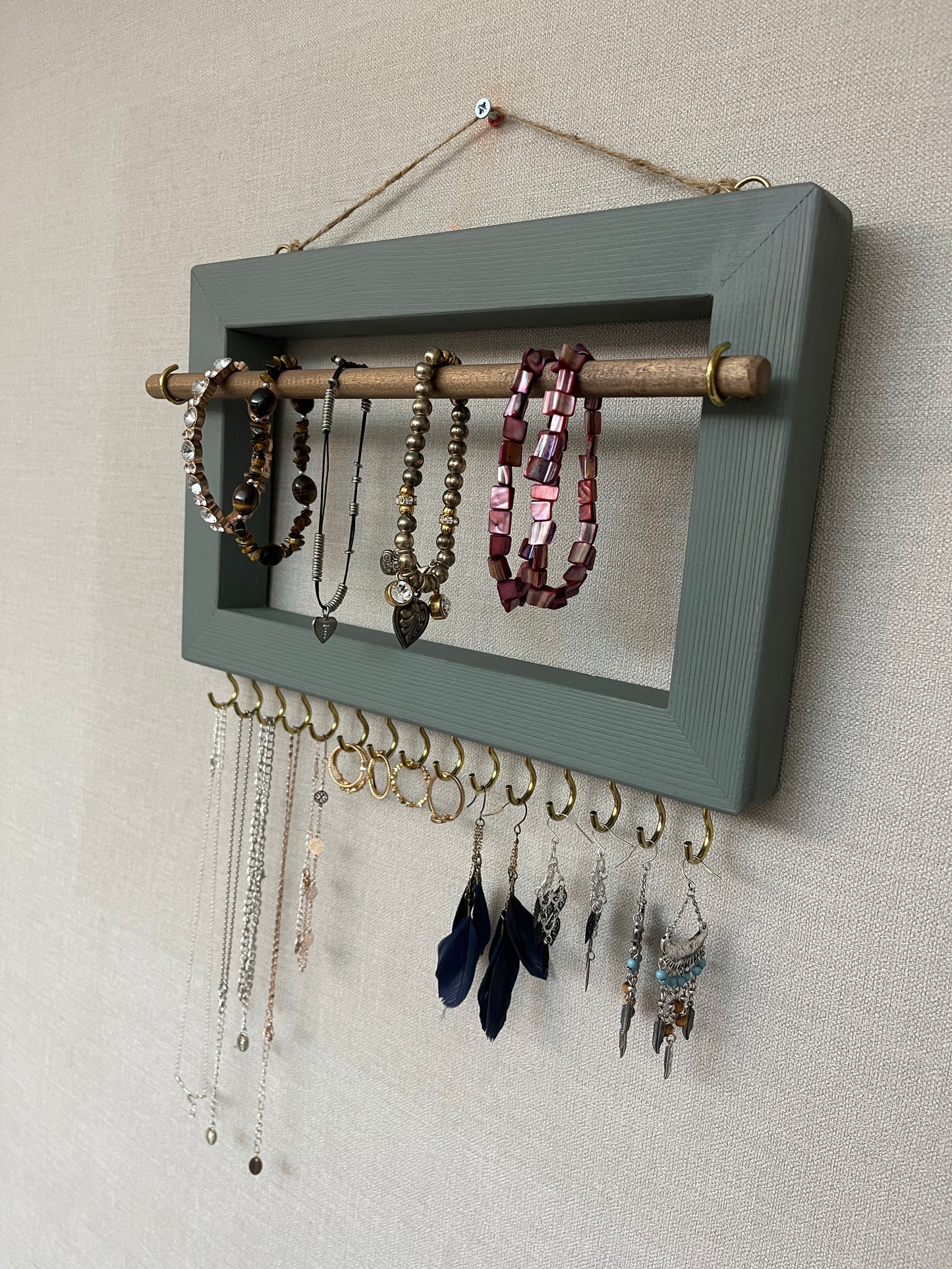 Handmade premium jewellery organizer crafted from timber, with hooks and a storage rod to safely store rings, necklaces, earrings, and bracelets. Available in 3 sizes. Frame design for wall mounting with D rings. Customizable color.