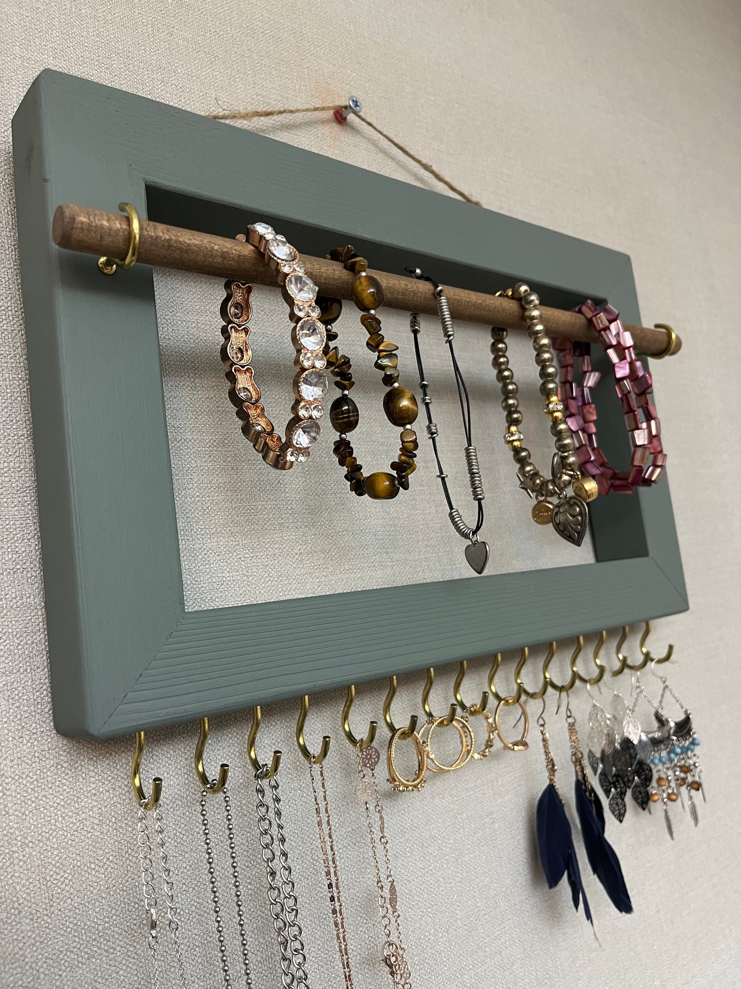 Handmade premium jewellery organizer crafted from timber, with hooks and a storage rod to safely store rings, necklaces, earrings, and bracelets. Available in 3 sizes. Frame design for wall mounting with D rings. Customizable color.