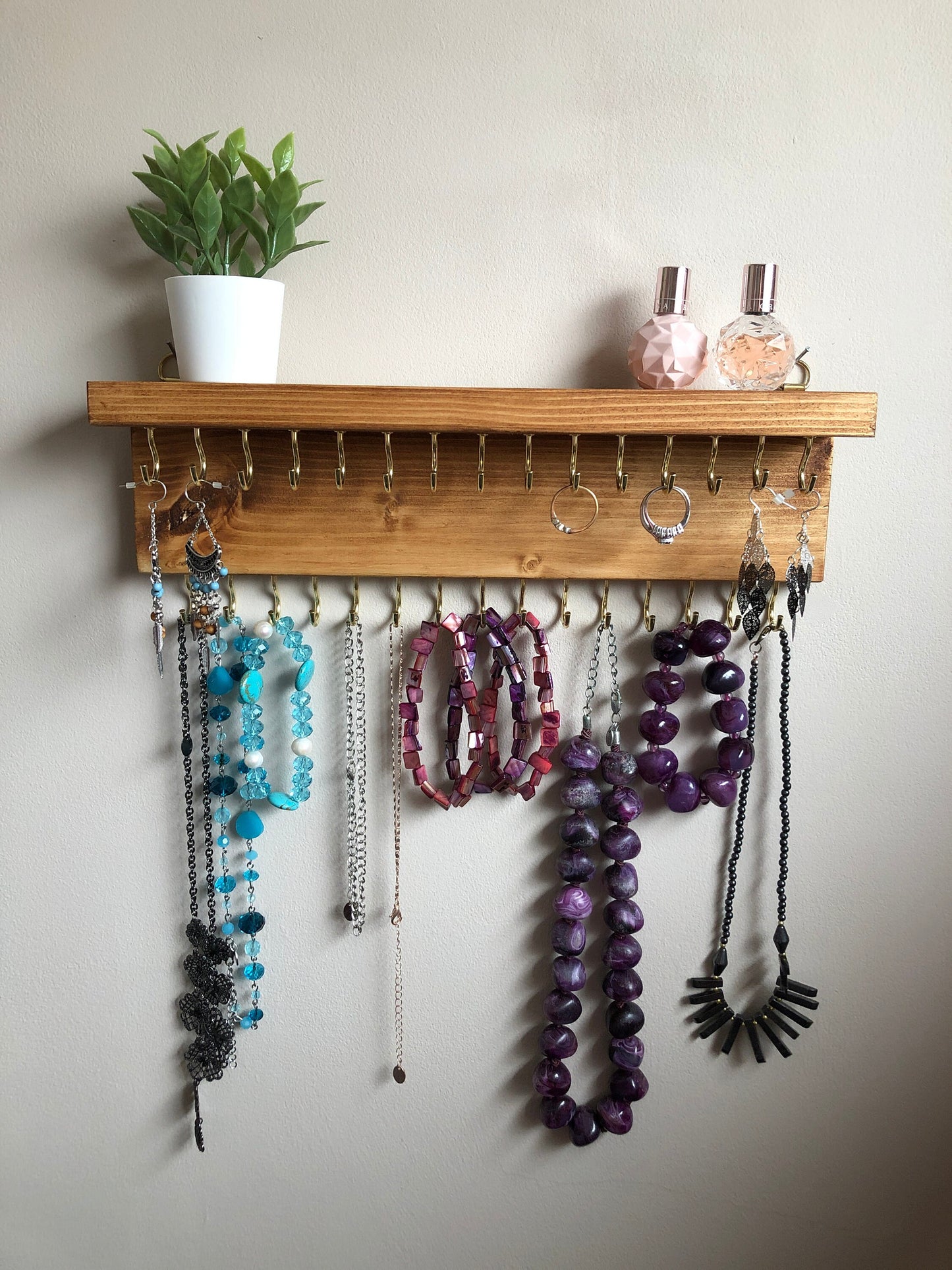 Wall-mounted jewellery organiser with 30 hooks, available in various colours including Woodland and Rustic Oak. Handcrafted from carefully selected timber, each piece boasts unique natural grain patterns. Customize with brass or upgrade to silver/chrome hooks and D rings