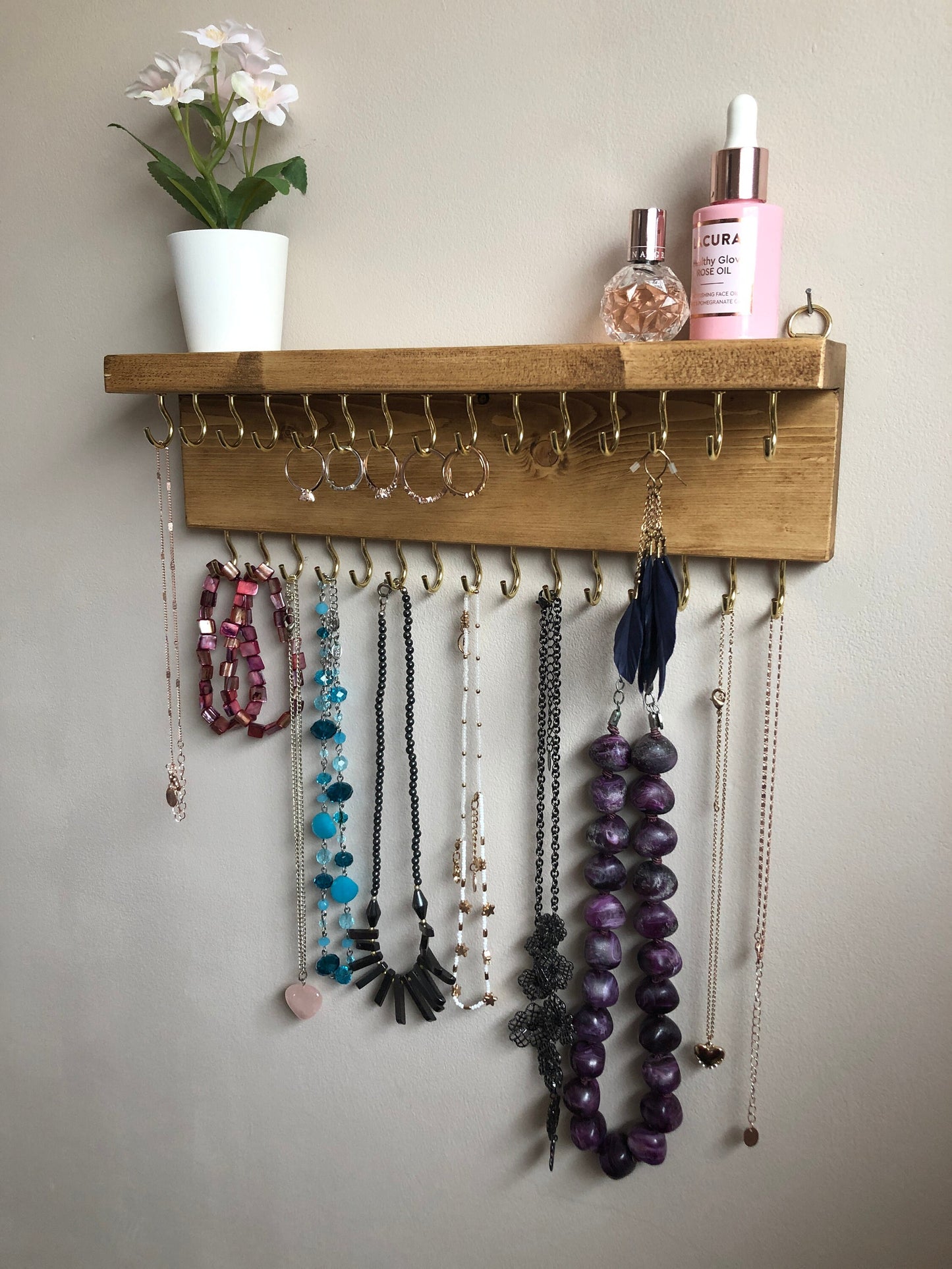Wall-mounted jewellery organiser with 30 hooks, available in various colours including Woodland and Rustic Oak. Handcrafted from carefully selected timber, each piece boasts unique natural grain patterns. Customize with brass or upgrade to silver/chrome hooks and D rings
