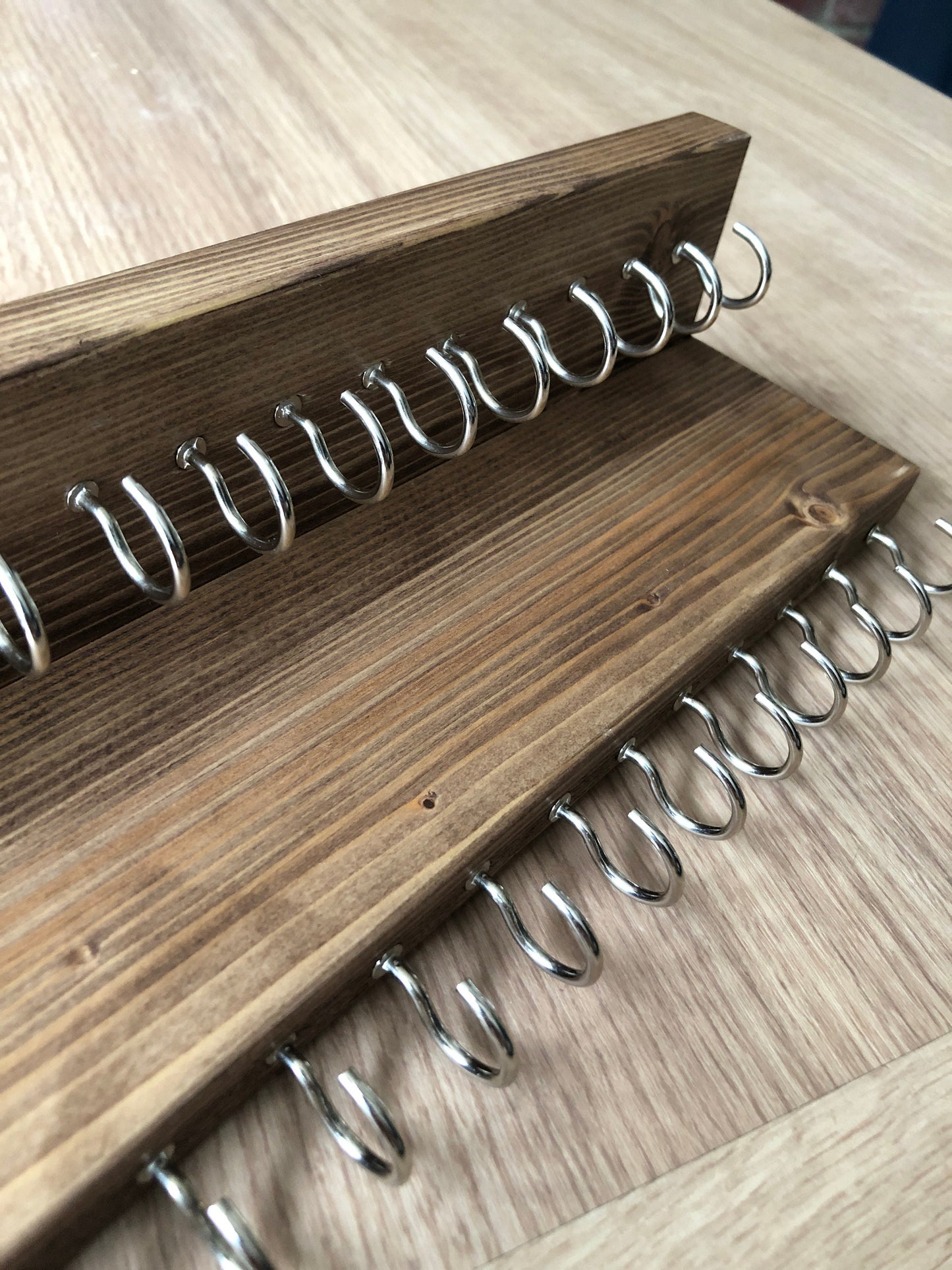 Wall-mounted jewellery organiser with 30 hooks, available in various colours including Woodland and Rustic Oak. Handcrafted from carefully selected timber, each piece boasts unique natural grain patterns. Customize with brass or upgrade to silver/chrome hooks and D rings
