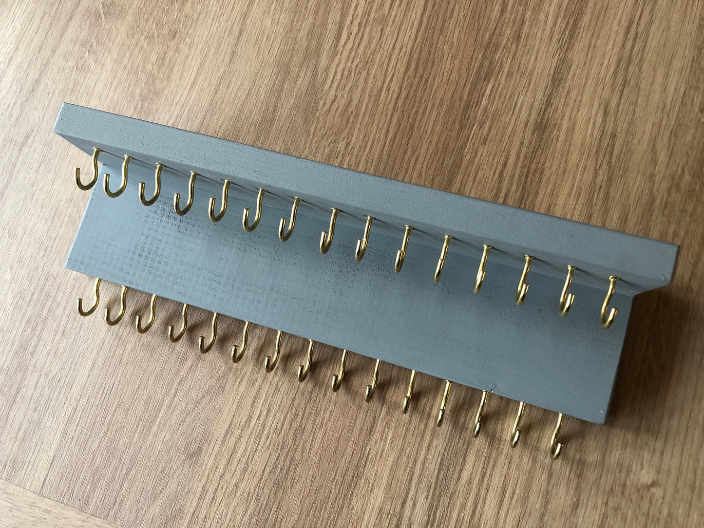 Small style shelf jewellery organiser with two rows of hooks for necklace and jewellry storage. Bottom row of hooks visible beneath the shelf, while another row is discreetly tucked underneath the top ledge. Ideal for keeping your accessories neatly organised and easily accessible.