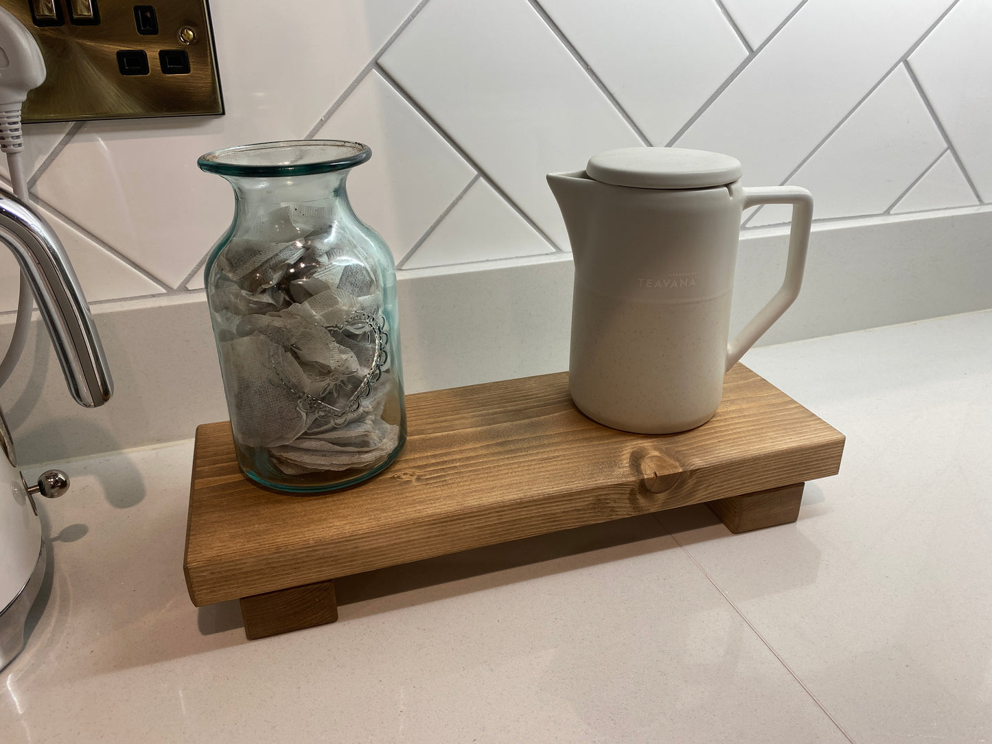 A wooden shelf that stands on two flat wooden legs. It is ideal for placing items on like bottles or candles.