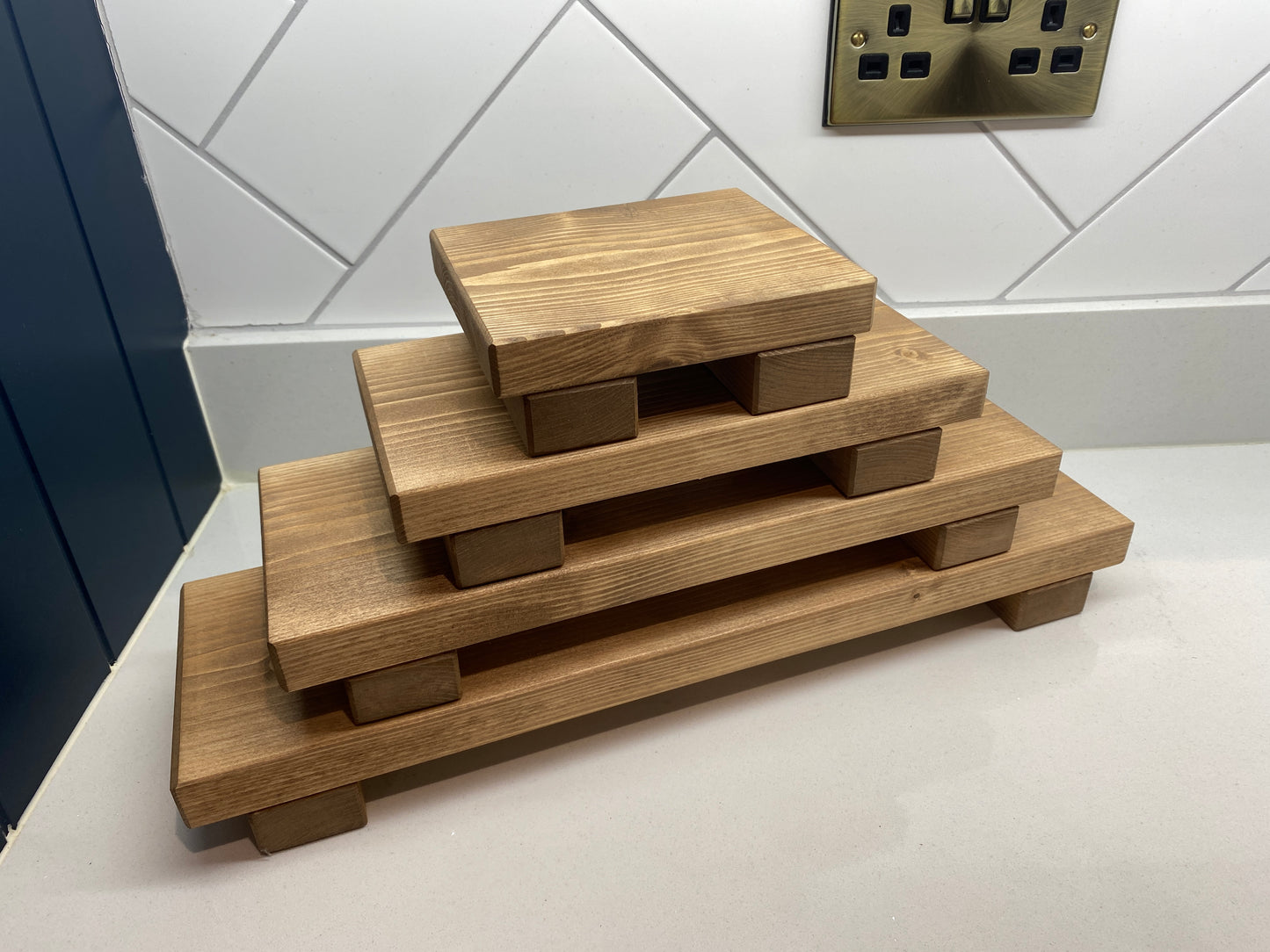 A wooden shelf that stands on two flat wooden legs. It is ideal for placing items on like bottles or candles.