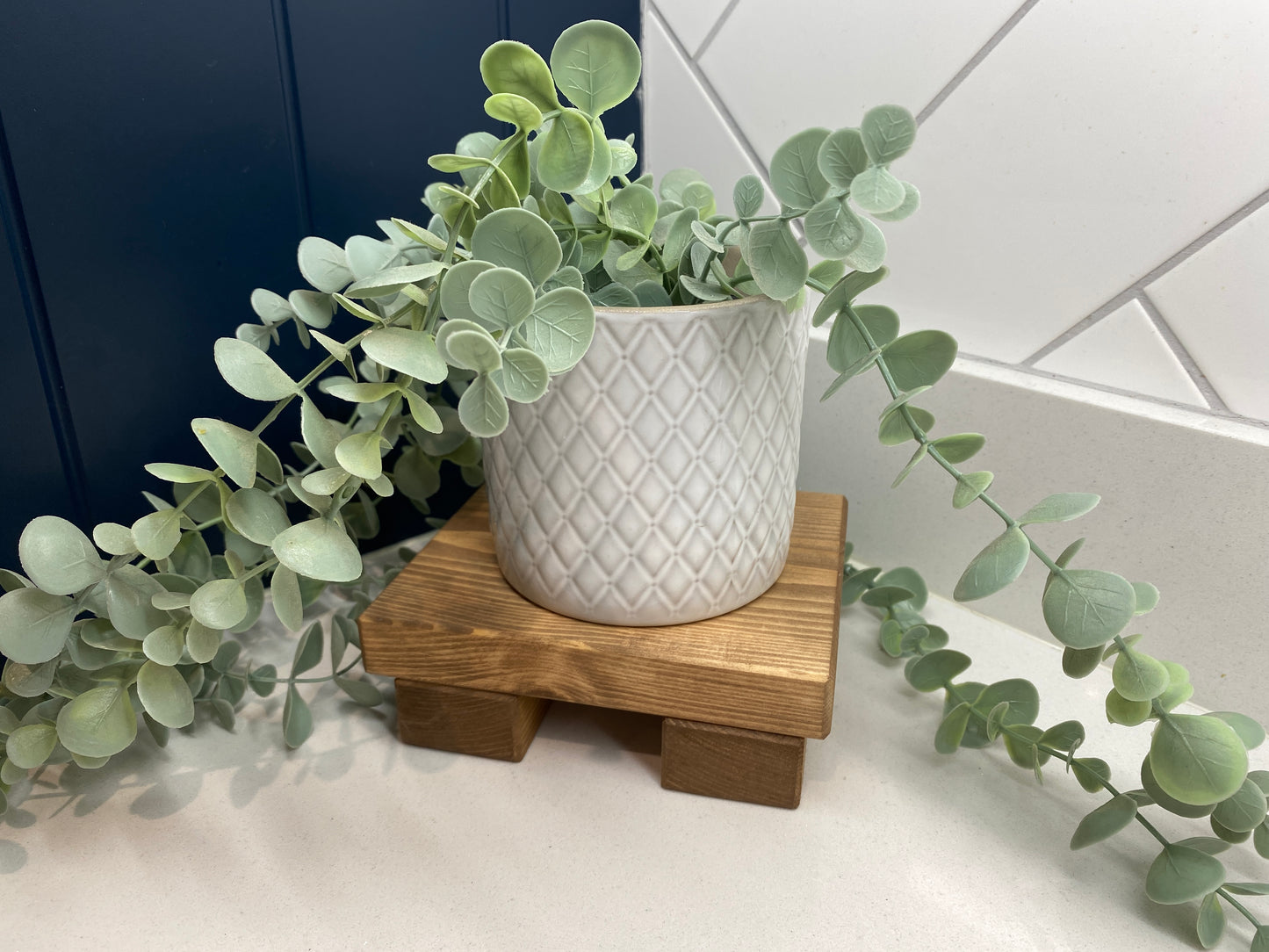 A wooden shelf that stands on two flat wooden legs. It is ideal for placing items on like bottles or candles.