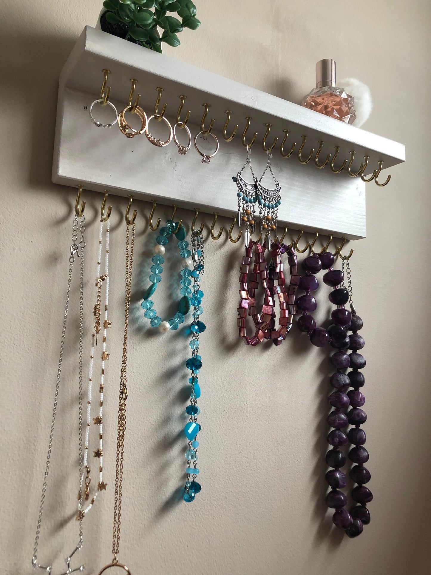 Small style shelf jewellery organiser with two rows of hooks for necklace and jewellry storage. Bottom row of hooks visible beneath the shelf, while another row is discreetly tucked underneath the top ledge. Ideal for keeping your accessories neatly organised and easily accessible.