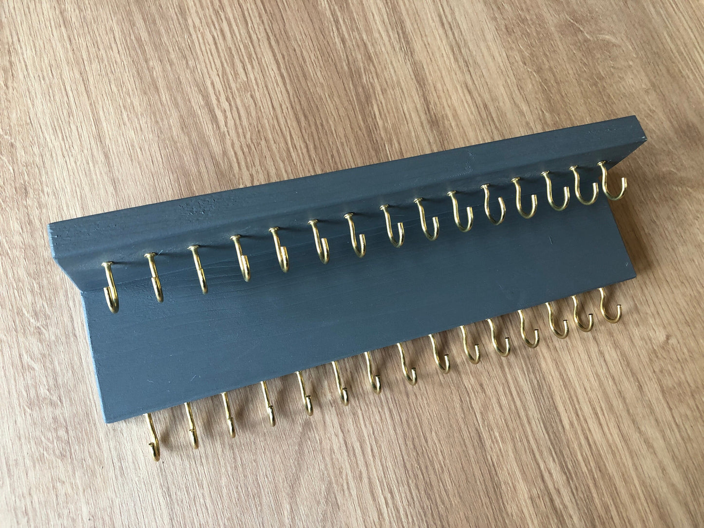Small style shelf jewellery organiser with two rows of hooks for necklace and jewellry storage. Bottom row of hooks visible beneath the shelf, while another row is discreetly tucked underneath the top ledge. Ideal for keeping your accessories neatly organised and easily accessible.