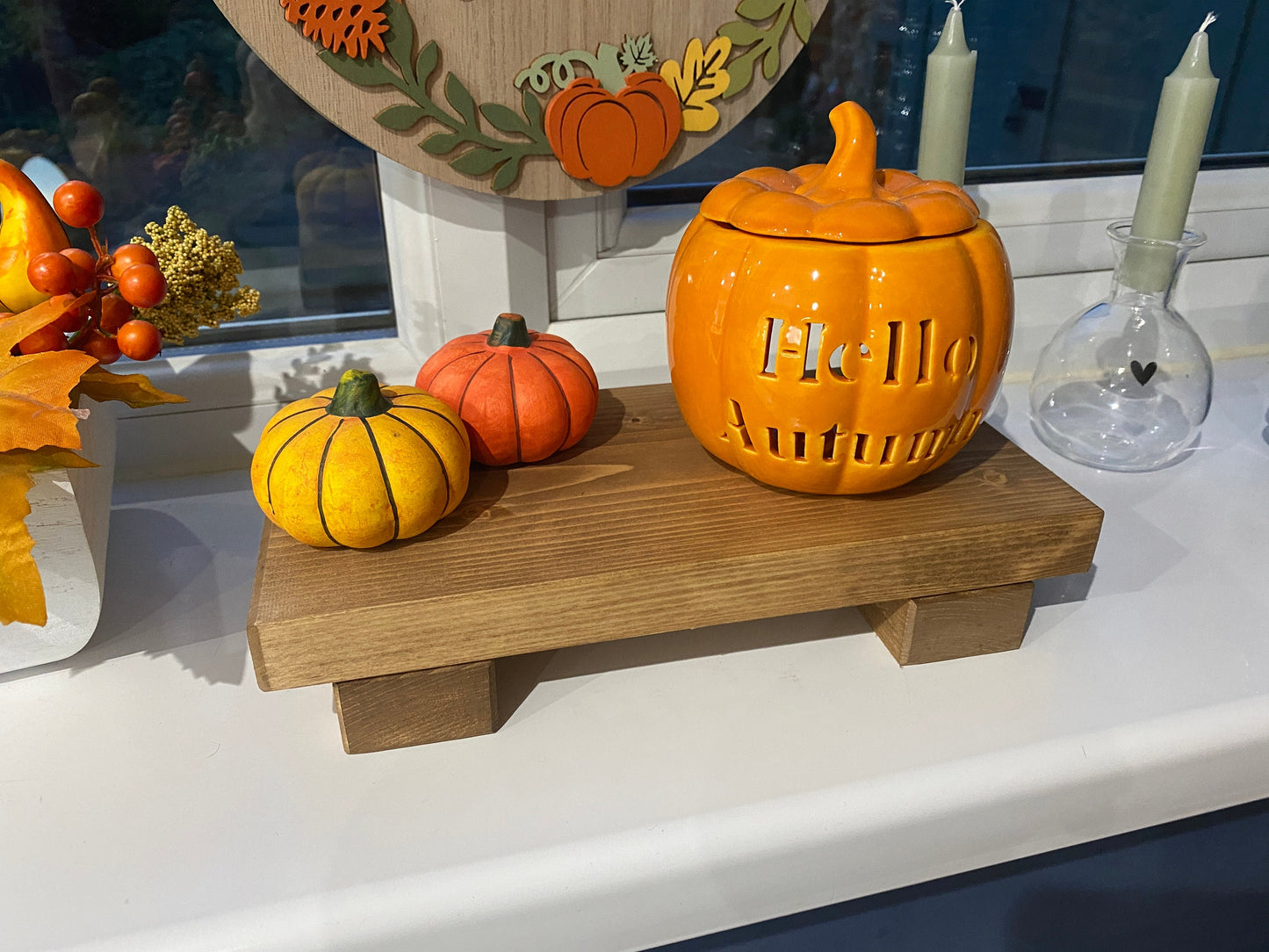 A wooden shelf that stands on two flat wooden legs. It is ideal for placing items on like bottles or candles.
