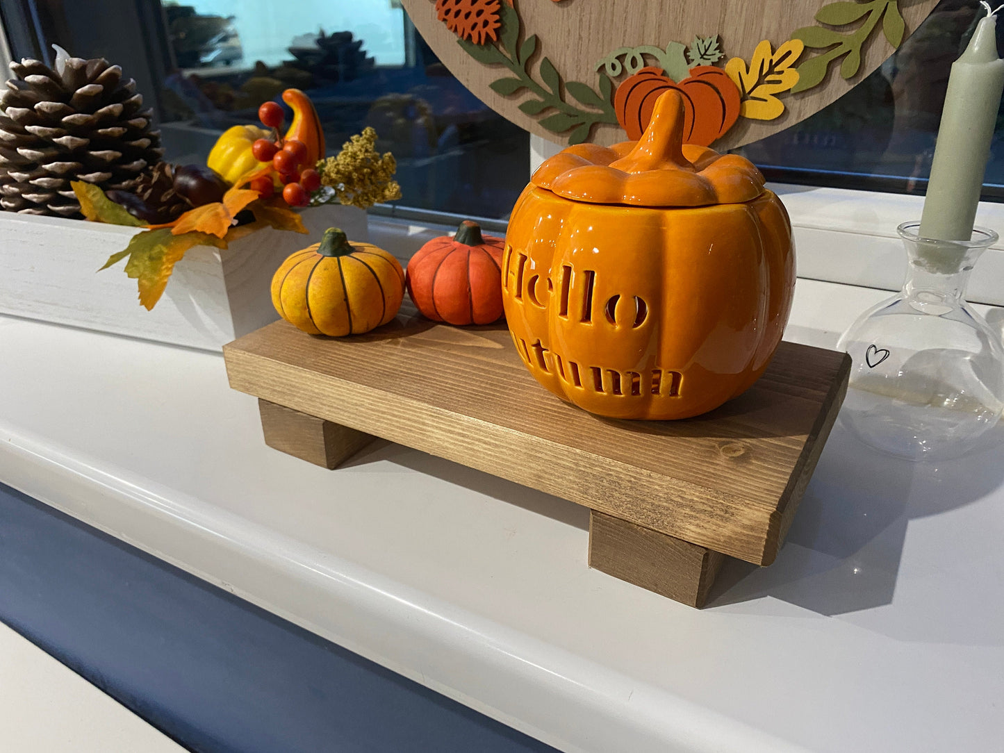 A wooden shelf that stands on two flat wooden legs. It is ideal for placing items on like bottles or candles.
