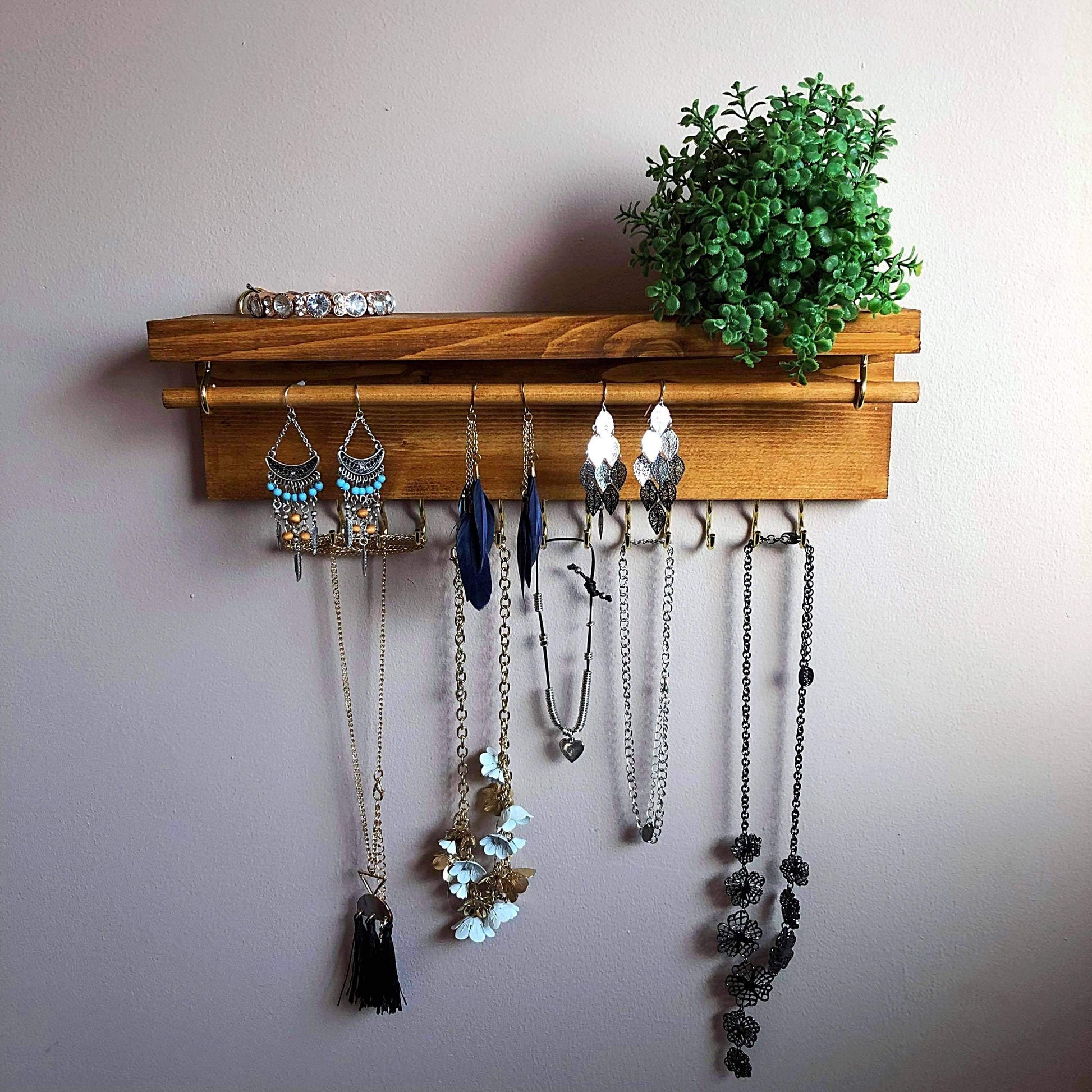  Handmade Wooden Jewellery Organiser and Earring Display featuring 13 brass hooks and a 9mm wooden dowel for versatile storage. Sleek Dark Walnut stain enhances its timeless elegance. Customize with brass or upgrade to silver/chrome hooks and D rings. Accessorize your decor effortlessly.
