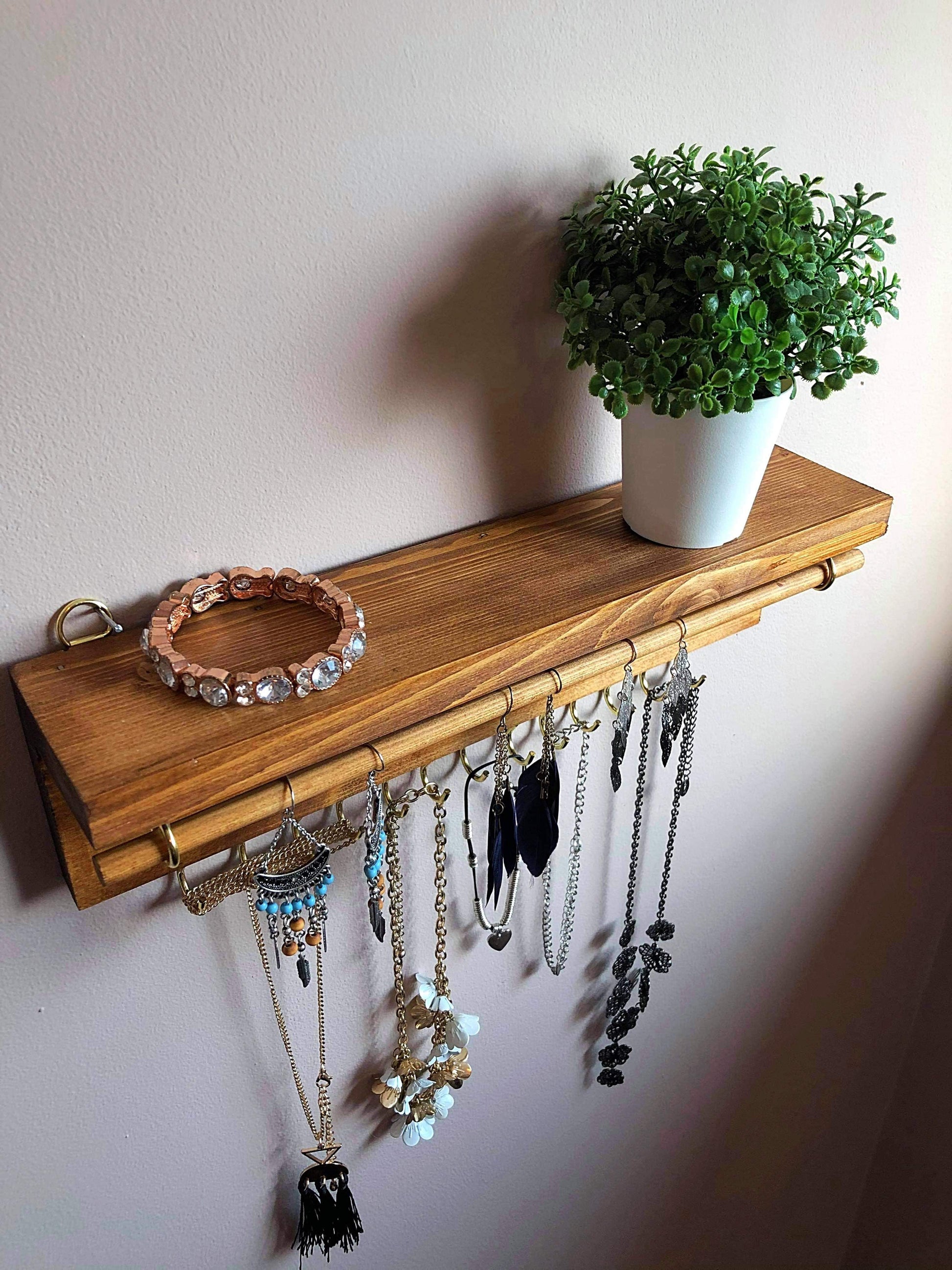  Handmade Wooden Jewellery Organiser and Earring Display featuring 13 brass hooks and a 9mm wooden dowel for versatile storage. Sleek Dark Walnut stain enhances its timeless elegance. Customize with brass or upgrade to silver/chrome hooks and D rings. Accessorize your decor effortlessly.