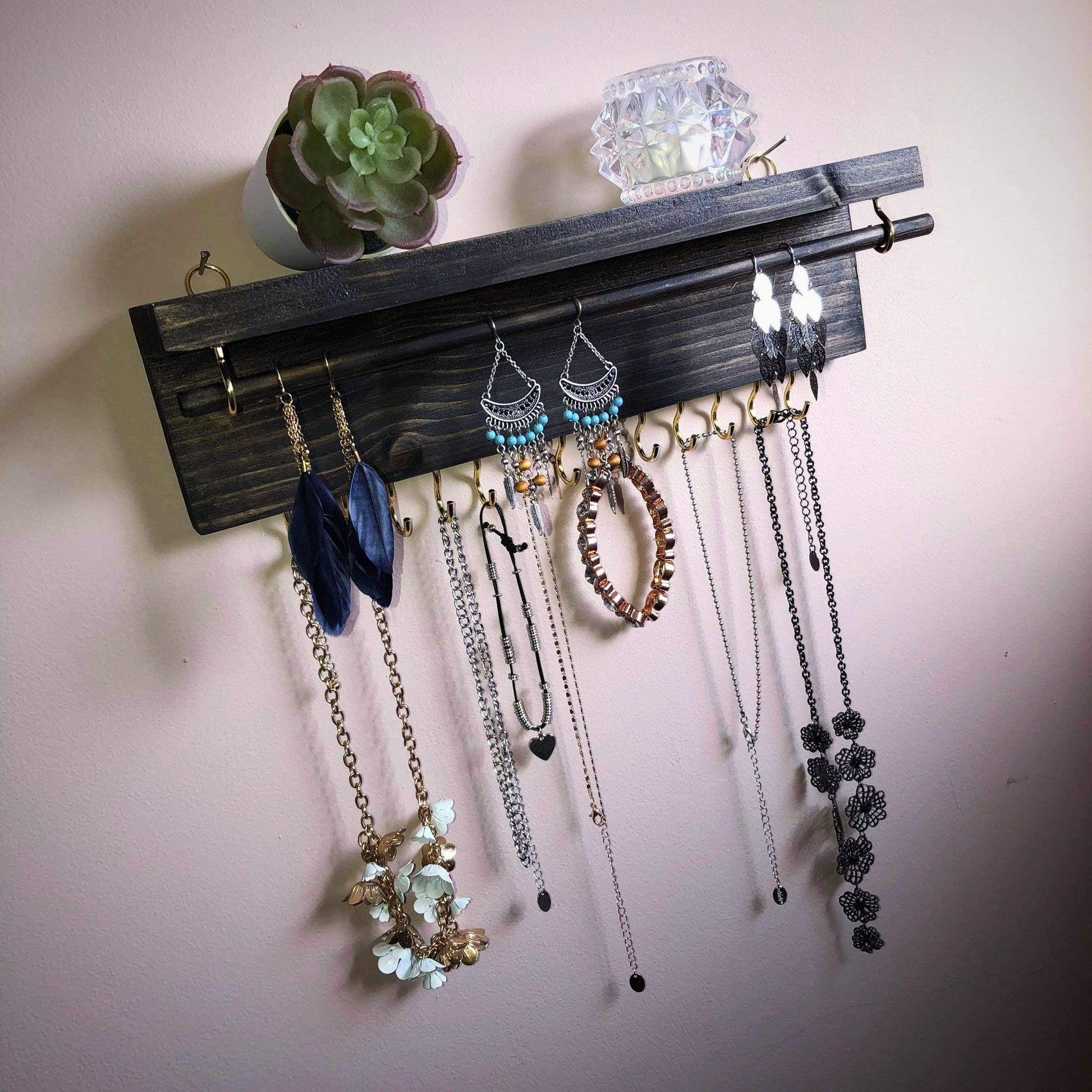  Handmade Wooden Jewellery Organiser and Earring Display featuring 13 brass hooks and a 9mm wooden dowel for versatile storage. Sleek Dark Walnut stain enhances its timeless elegance. Customize with brass or upgrade to silver/chrome hooks and D rings. Accessorize your decor effortlessly.