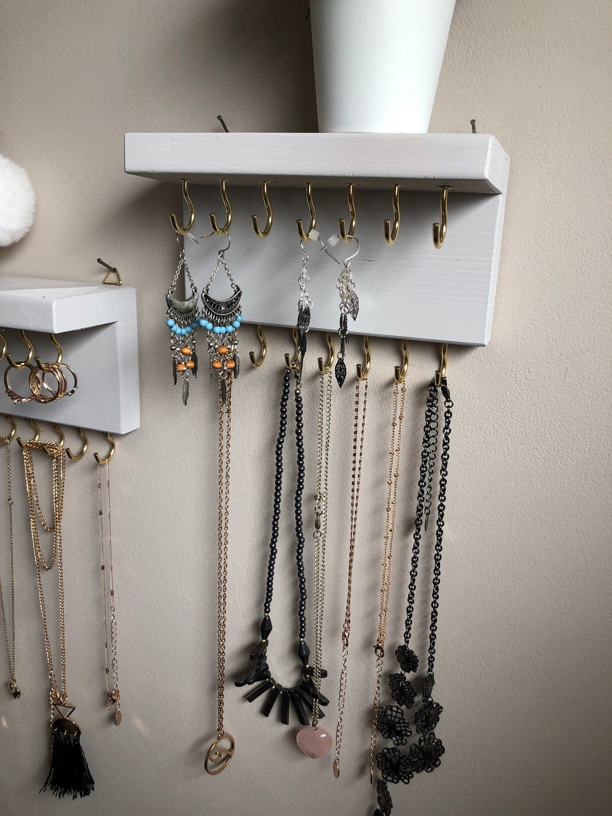 Each organizer, measuring 16cm in length, provides compact storage adaptable to any wall space, boasting a total of 28 hooks for ample room to elegantly display your favorite pieces. Featuring convenient D rings for easy hanging, these organizers double as additional shelving, perfect for storing smaller accessories. Handcrafted from carefully selected timber, each piece exudes natural charm with unique grain patterns, available in enchanting colors like Woodland, Rustic Oak, and Ebony.