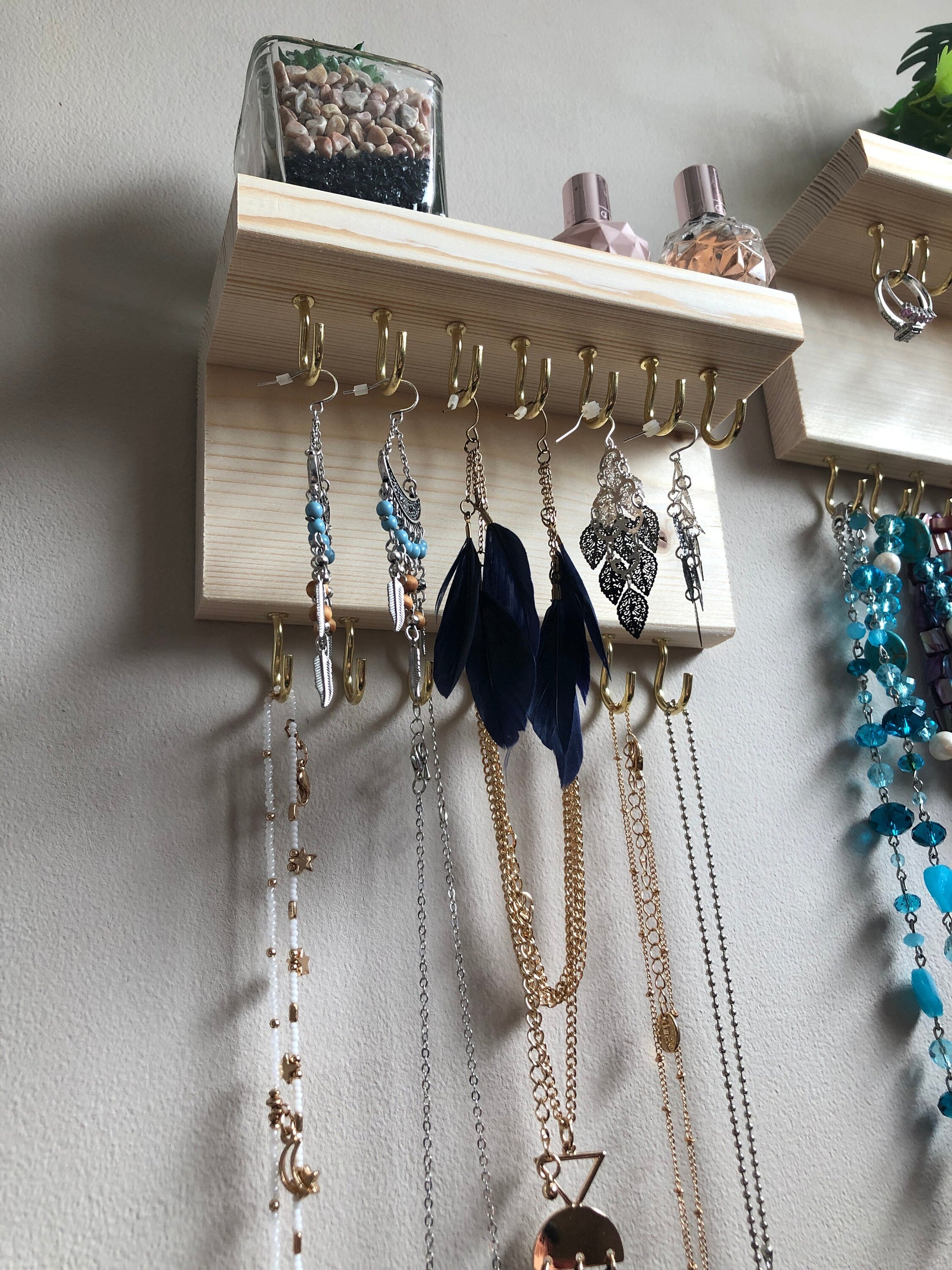 Each organizer, measuring 16cm in length, provides compact storage adaptable to any wall space, boasting a total of 28 hooks for ample room to elegantly display your favorite pieces. Featuring convenient D rings for easy hanging, these organizers double as additional shelving, perfect for storing smaller accessories. Handcrafted from carefully selected timber, each piece exudes natural charm with unique grain patterns, available in enchanting colors like Woodland, Rustic Oak, and Ebony.