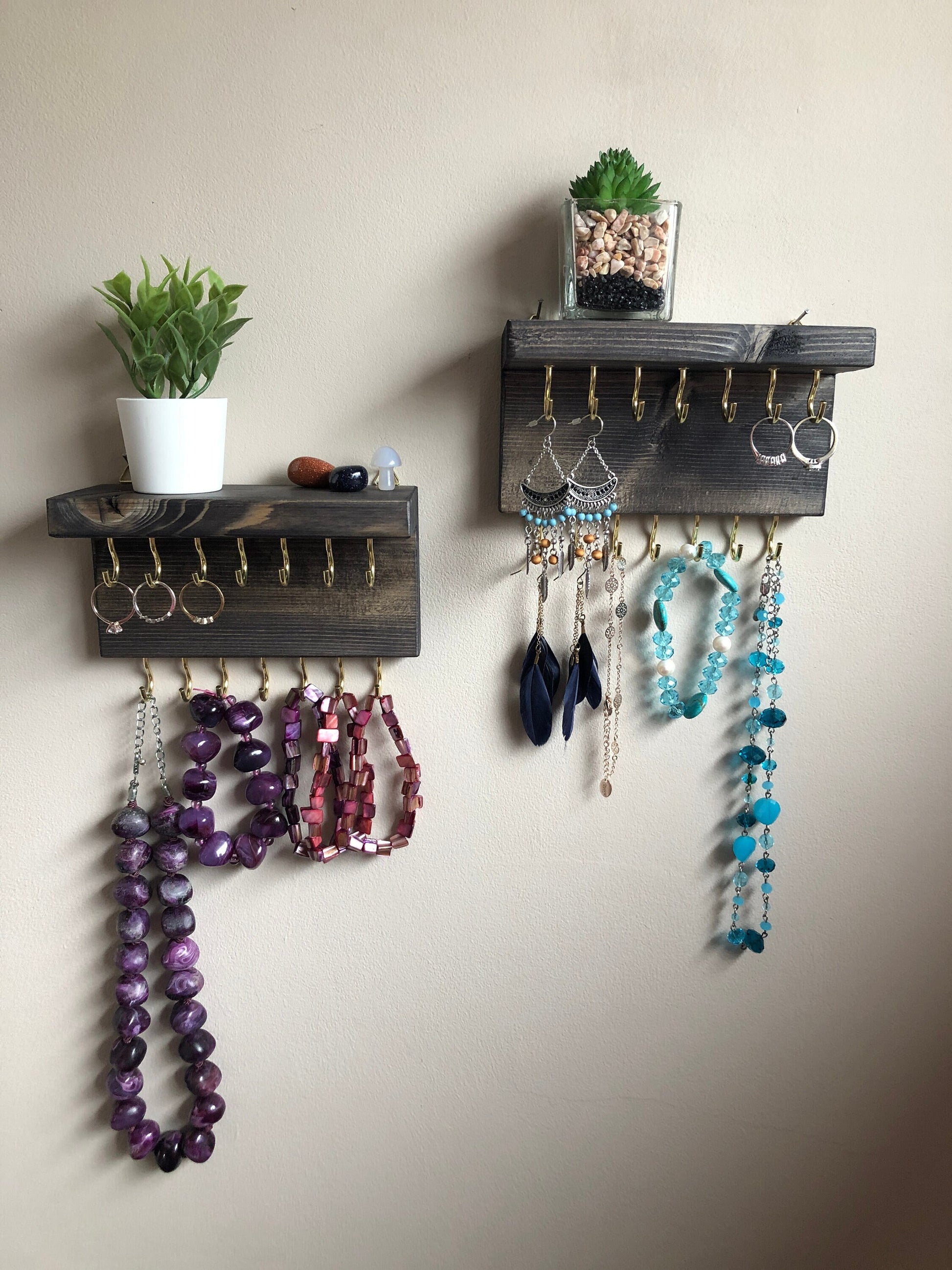 Each organizer, measuring 16cm in length, provides compact storage adaptable to any wall space, boasting a total of 28 hooks for ample room to elegantly display your favorite pieces. Featuring convenient D rings for easy hanging, these organizers double as additional shelving, perfect for storing smaller accessories. Handcrafted from carefully selected timber, each piece exudes natural charm with unique grain patterns, available in enchanting colors like Woodland, Rustic Oak, and Ebony.