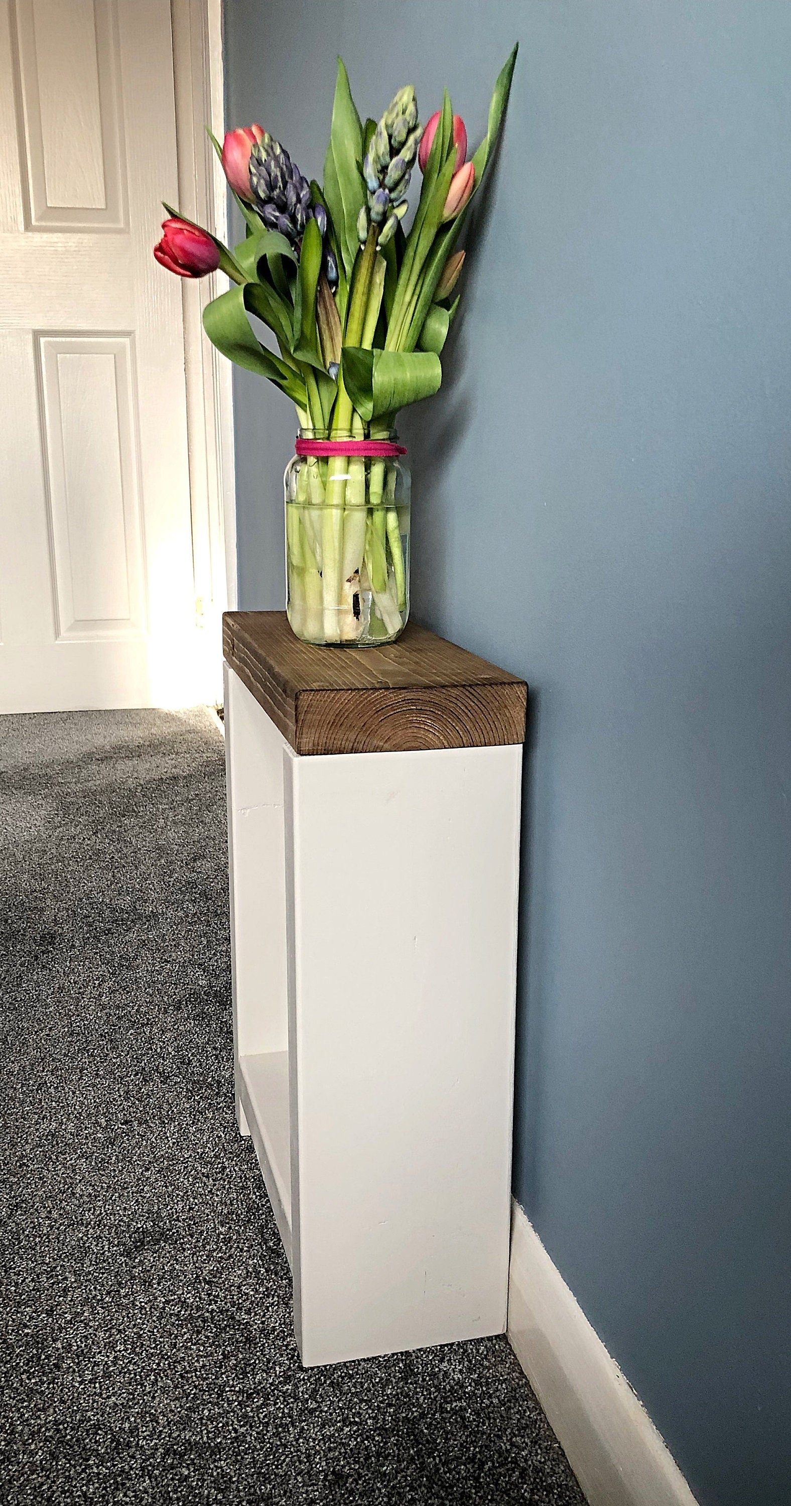 Handmade narrow side table crafted from carefully selected timber, versatile for various settings Features spacious top for plants or candles and low shelf for books or tall vase. Finished with two-tone effect: base in select Farrow and Ball colors, top in Dark Oak or Medium Oak wood dye. Dimensions: H: 44.5cm, W: 33cm, D: 14cm, with 33cm height between shelf and top. Enjoy FREE delivery on all handmade items. Order now for a carefully packaged product crafted with love. Build time: 3-4 weeks.