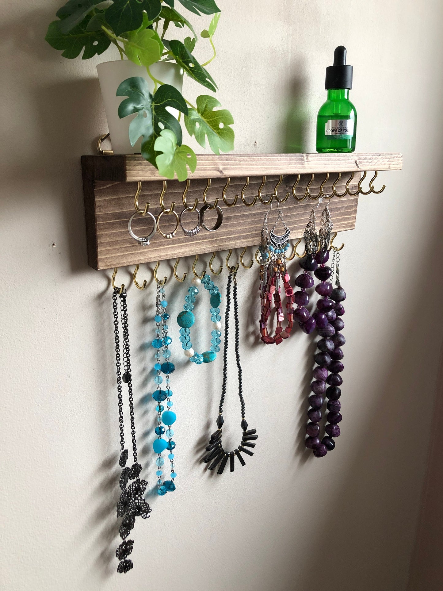 Wall-mounted jewellery organiser with 30 hooks, available in various colours including Woodland and Rustic Oak. Handcrafted from carefully selected timber, each piece boasts unique natural grain patterns. Customize with brass or upgrade to silver/chrome hooks and D rings