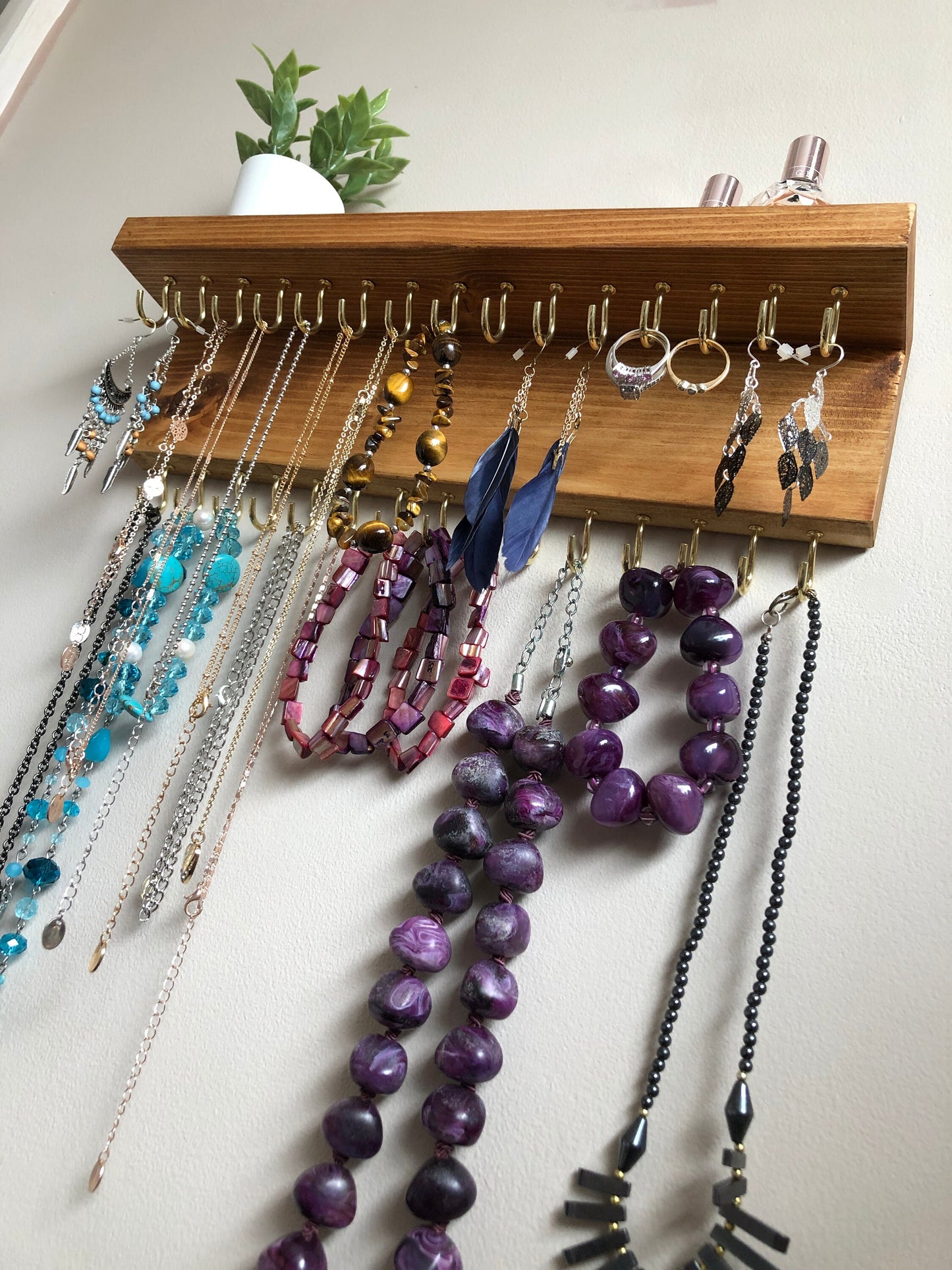 Wall-mounted jewellery organiser with 30 hooks, available in various colours including Woodland and Rustic Oak. Handcrafted from carefully selected timber, each piece boasts unique natural grain patterns. Customize with brass or upgrade to silver/chrome hooks and D rings