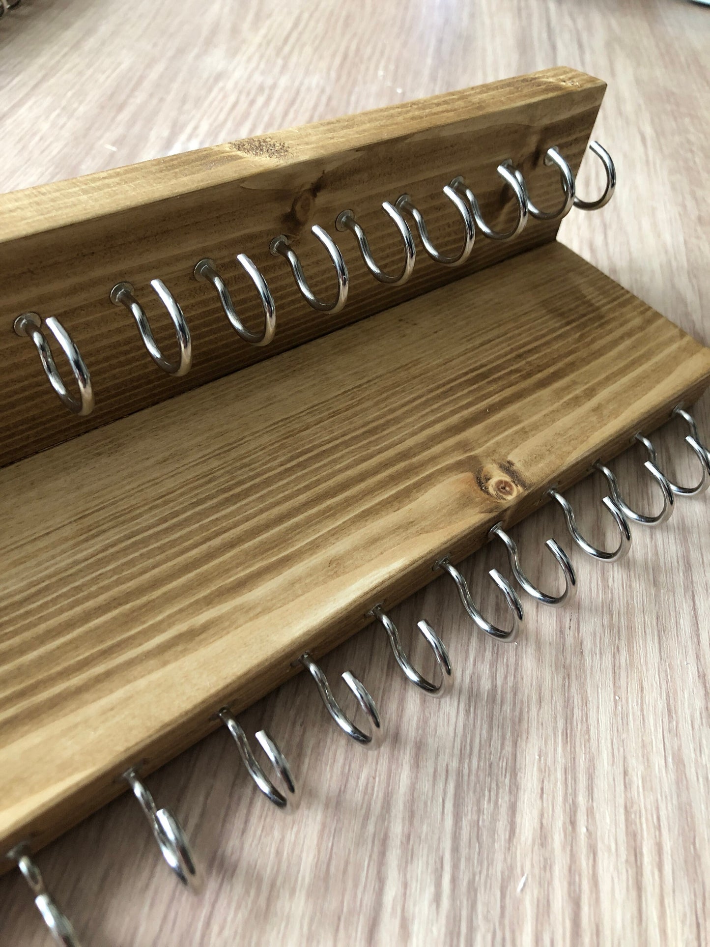 Wall-mounted jewellery organiser with 30 hooks, available in various colours including Woodland and Rustic Oak. Handcrafted from carefully selected timber, each piece boasts unique natural grain patterns. Customize with brass or upgrade to silver/chrome hooks and D rings
