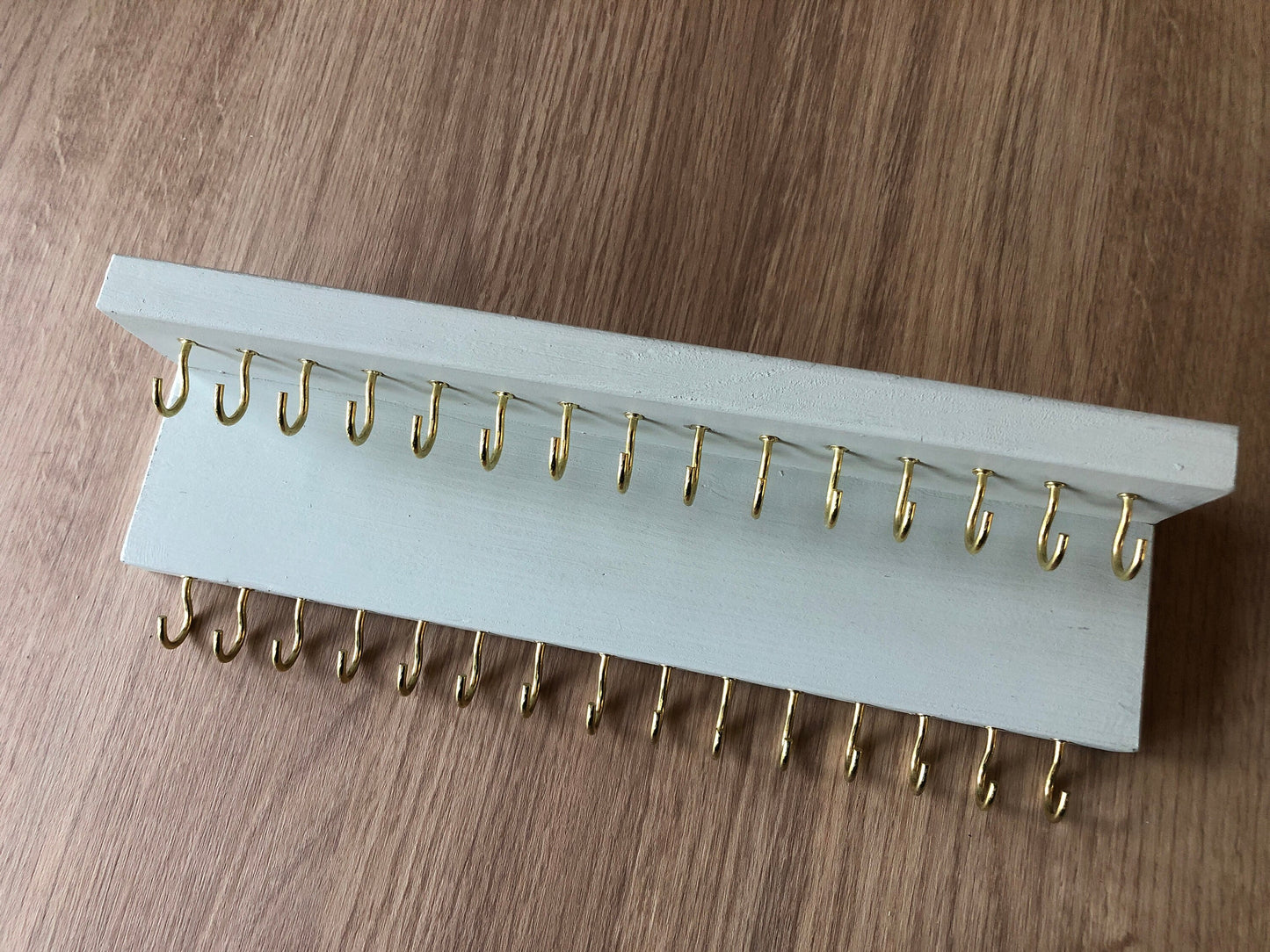 Small style shelf jewellery organiser with two rows of hooks for necklace and jewellry storage. Bottom row of hooks visible beneath the shelf, while another row is discreetly tucked underneath the top ledge. Ideal for keeping your accessories neatly organised and easily accessible.