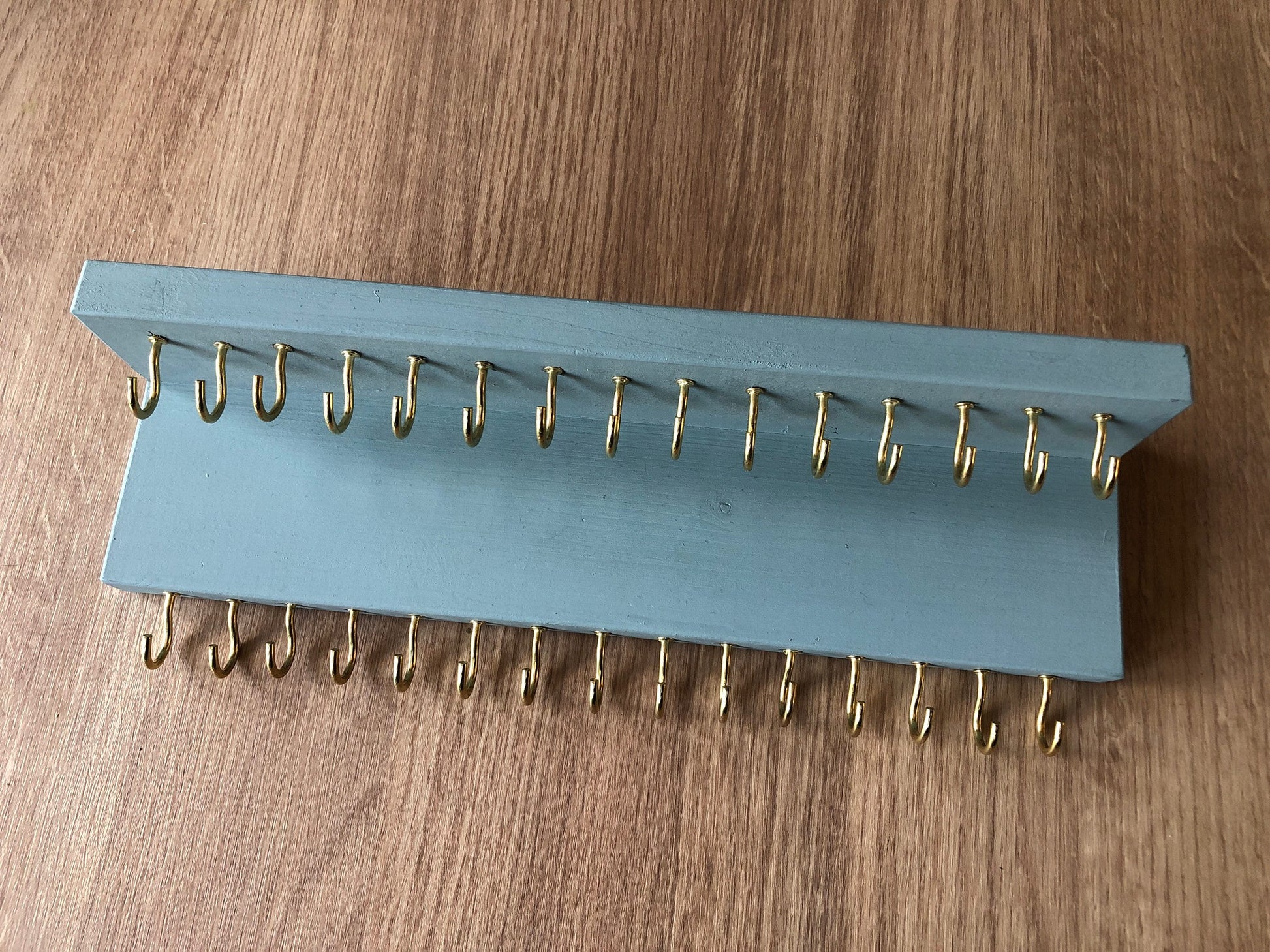 Small style shelf jewellery organiser with two rows of hooks for necklace and jewellry storage. Bottom row of hooks visible beneath the shelf, while another row is discreetly tucked underneath the top ledge. Ideal for keeping your accessories neatly organised and easily accessible.