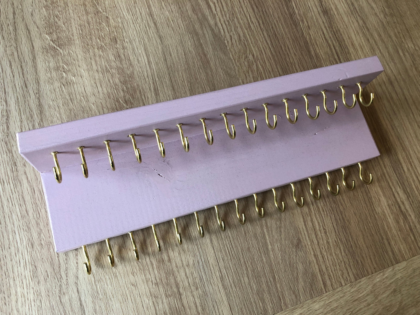 Small style shelf jewellery organiser with two rows of hooks for necklace and jewellry storage. Bottom row of hooks visible beneath the shelf, while another row is discreetly tucked underneath the top ledge. Ideal for keeping your accessories neatly organised and easily accessible.