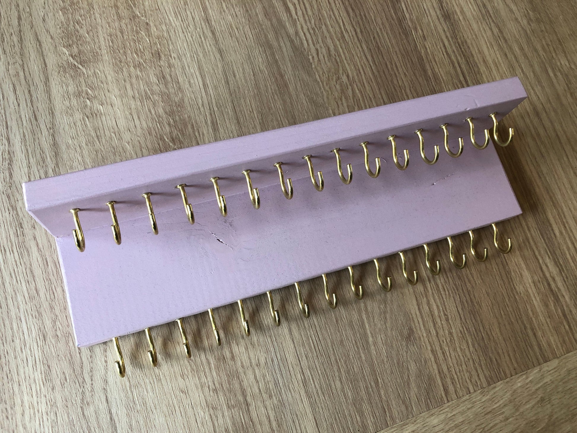 Small style shelf jewellery organiser with two rows of hooks for necklace and jewellry storage. Bottom row of hooks visible beneath the shelf, while another row is discreetly tucked underneath the top ledge. Ideal for keeping your accessories neatly organised and easily accessible.