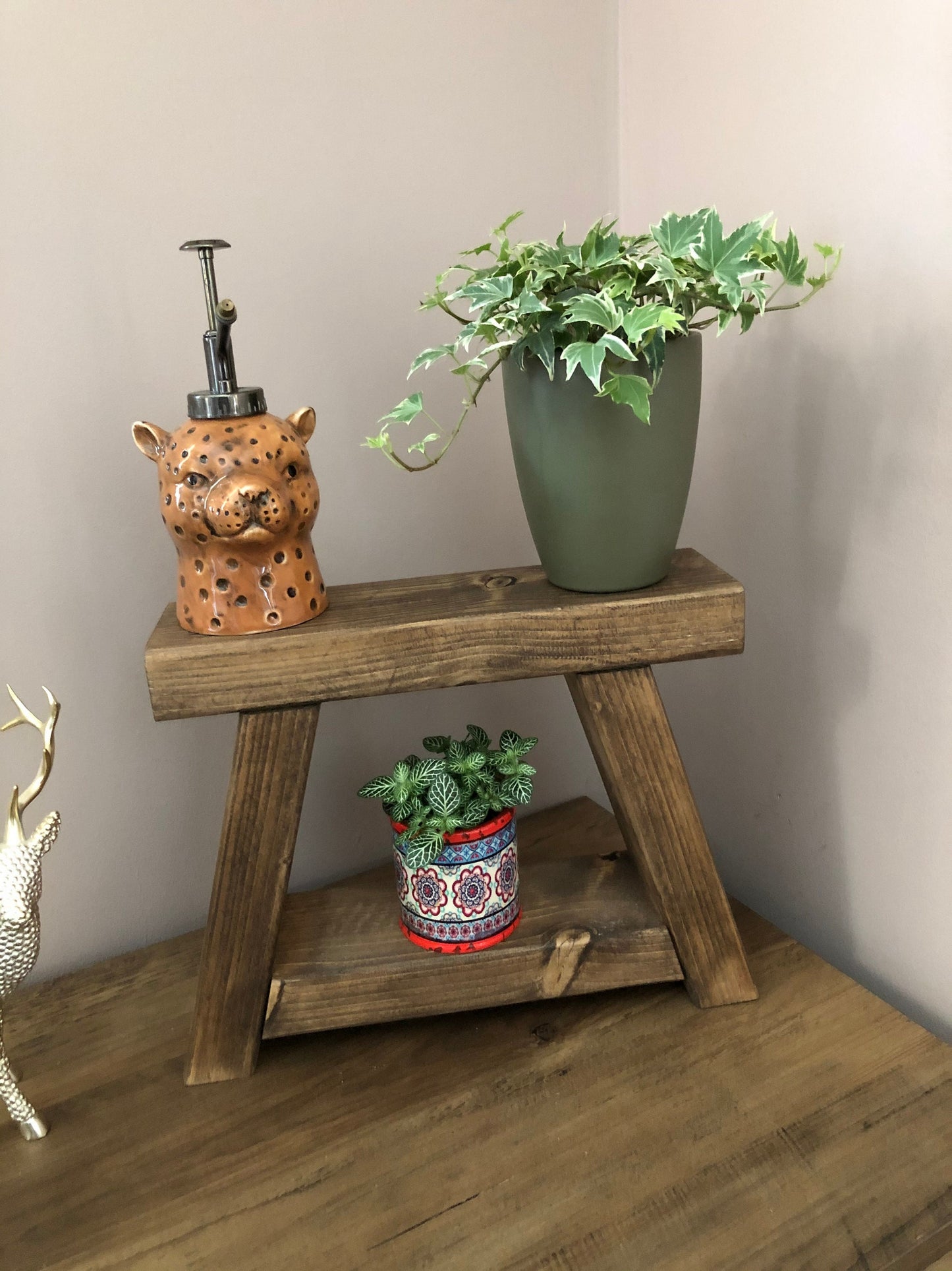 Handmade small rustic-style display stool with chunky shelves, perfect for living rooms, kitchens, and bathrooms. Ideal for house plants, beauty products, cosmetics, and candles. Made to order with options of Rustic Oak, Fir Cone, or Plain Untreated finish. Measurements: Total Height 10 inches, Width 11.75 inches, Depth 3.5 inches. Crafted with care, ensuring each piece is inspected for beauty and quality.