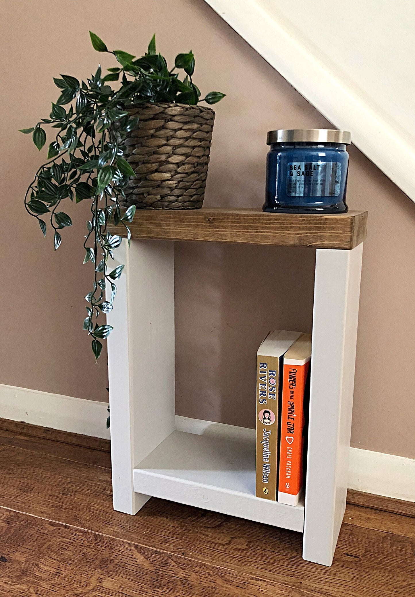 Handmade narrow side table crafted from carefully selected timber, versatile for various settings Features spacious top for plants or candles and low shelf for books or tall vase. Finished with two-tone effect: base in select Farrow and Ball colors, top in Dark Oak or Medium Oak wood dye. Dimensions: H: 44.5cm, W: 33cm, D: 14cm, with 33cm height between shelf and top. Enjoy FREE delivery on all handmade items. Order now for a carefully packaged product crafted with love. Build time: 3-4 weeks.
