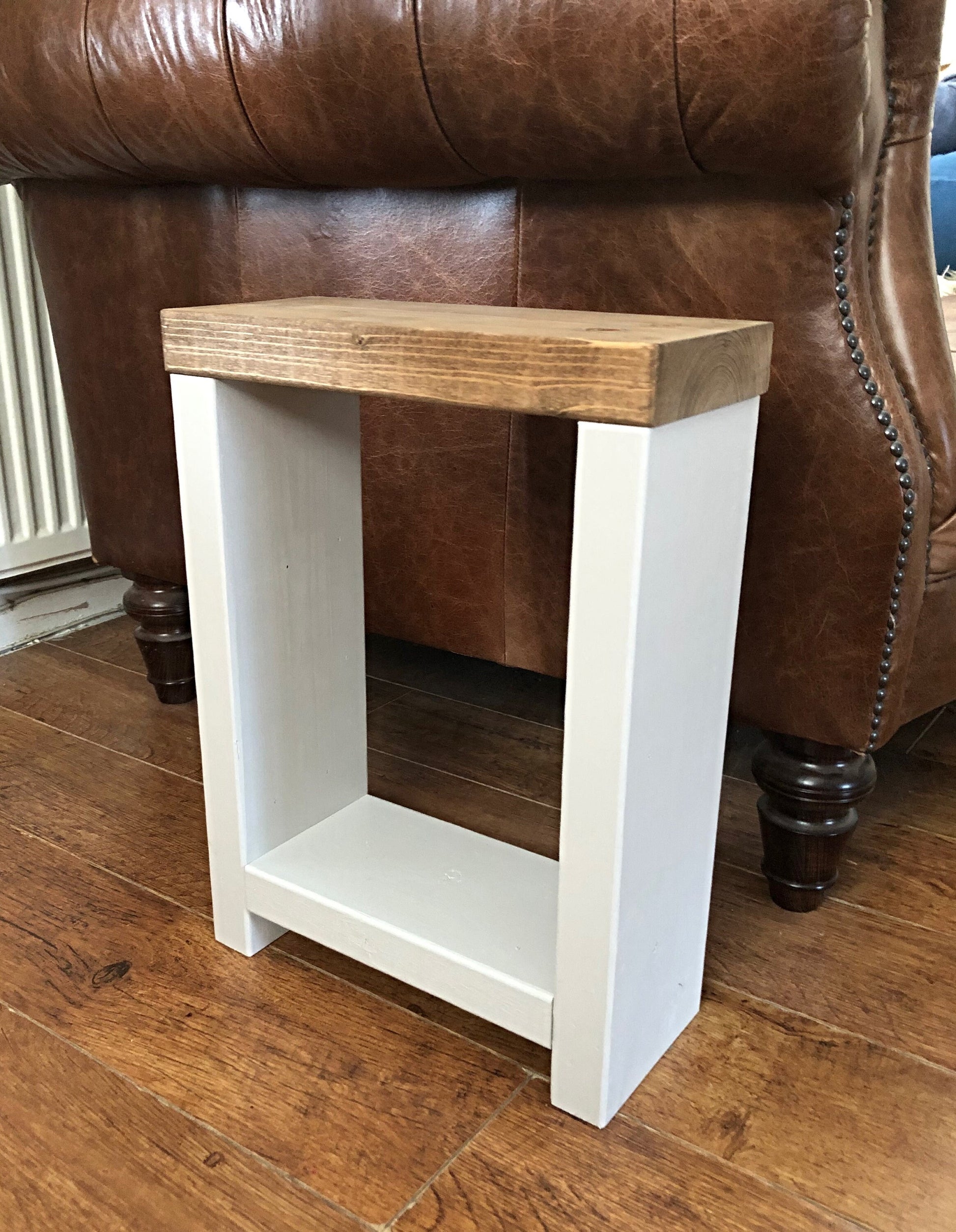 Handmade narrow side table crafted from carefully selected timber, versatile for various settings Features spacious top for plants or candles and low shelf for books or tall vase. Finished with two-tone effect: base in select Farrow and Ball colors, top in Dark Oak or Medium Oak wood dye. Dimensions: H: 44.5cm, W: 33cm, D: 14cm, with 33cm height between shelf and top. Enjoy FREE delivery on all handmade items. Order now for a carefully packaged product crafted with love. Build time: 3-4 weeks.