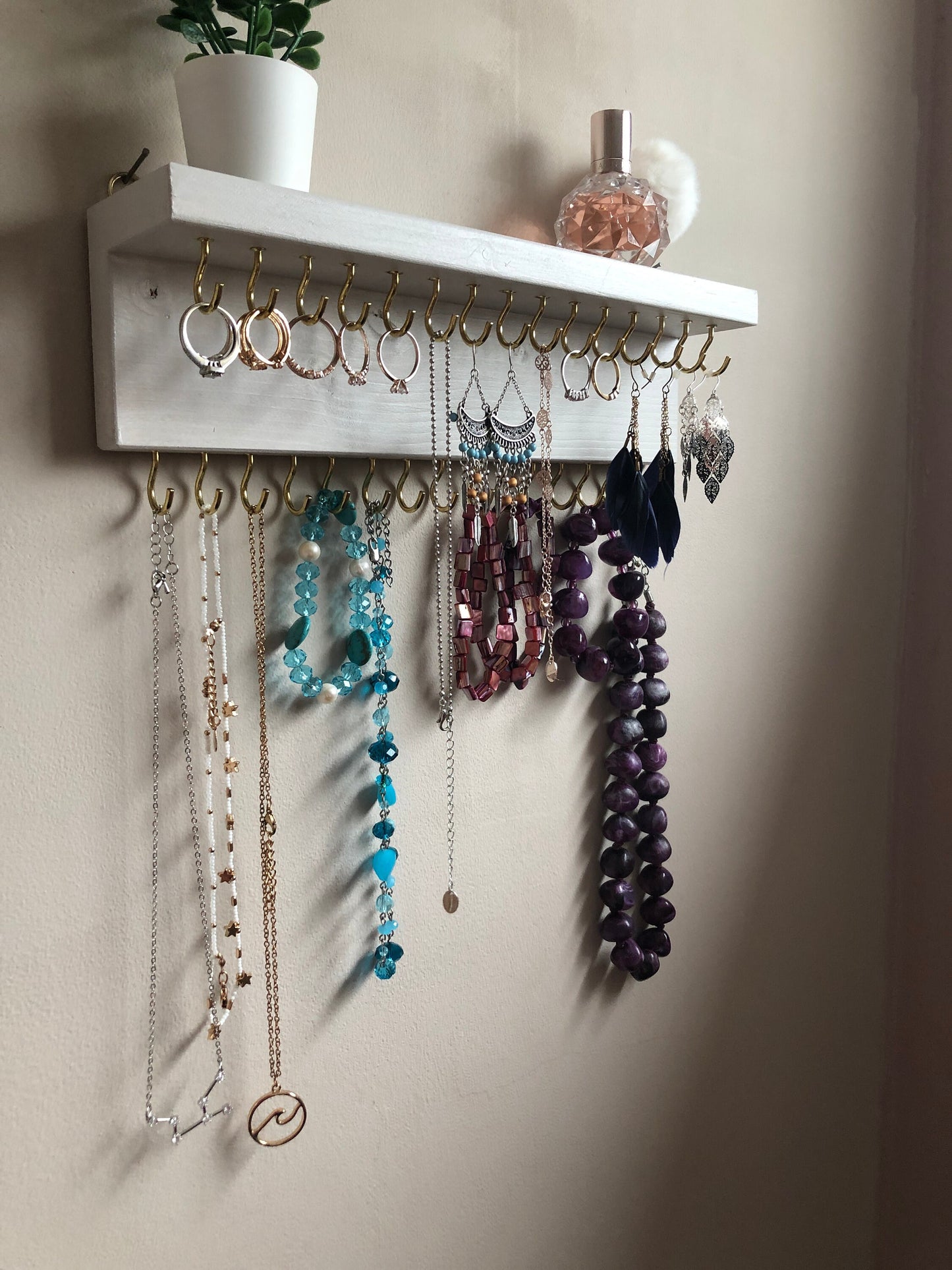 Small style shelf jewellery organiser with two rows of hooks for necklace and jewellry storage. Bottom row of hooks visible beneath the shelf, while another row is discreetly tucked underneath the top ledge. Ideal for keeping your accessories neatly organised and easily accessible.