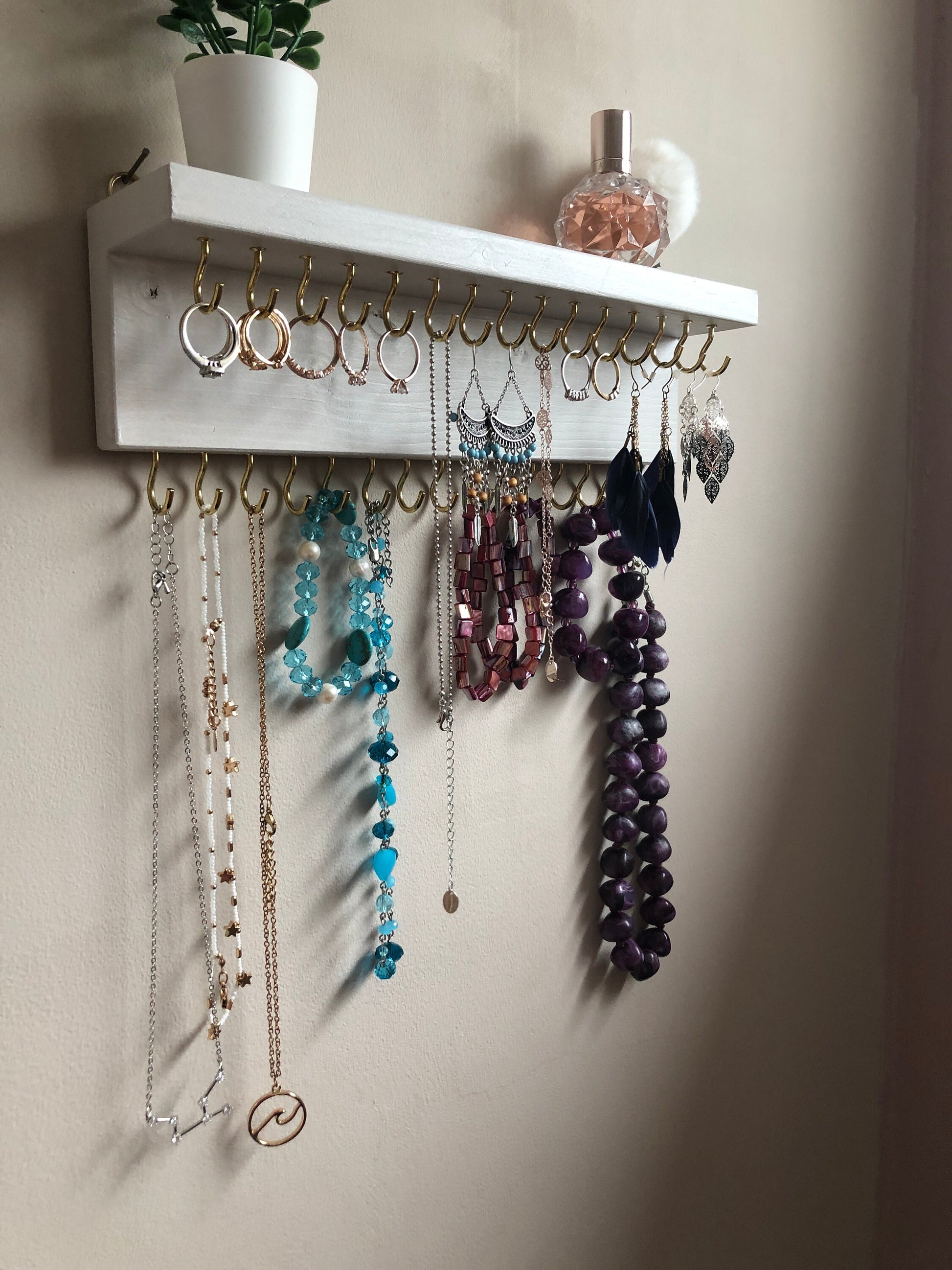 Small style shelf jewellery organiser with two rows of hooks for necklace and jewellry storage. Bottom row of hooks visible beneath the shelf, while another row is discreetly tucked underneath the top ledge. Ideal for keeping your accessories neatly organised and easily accessible.