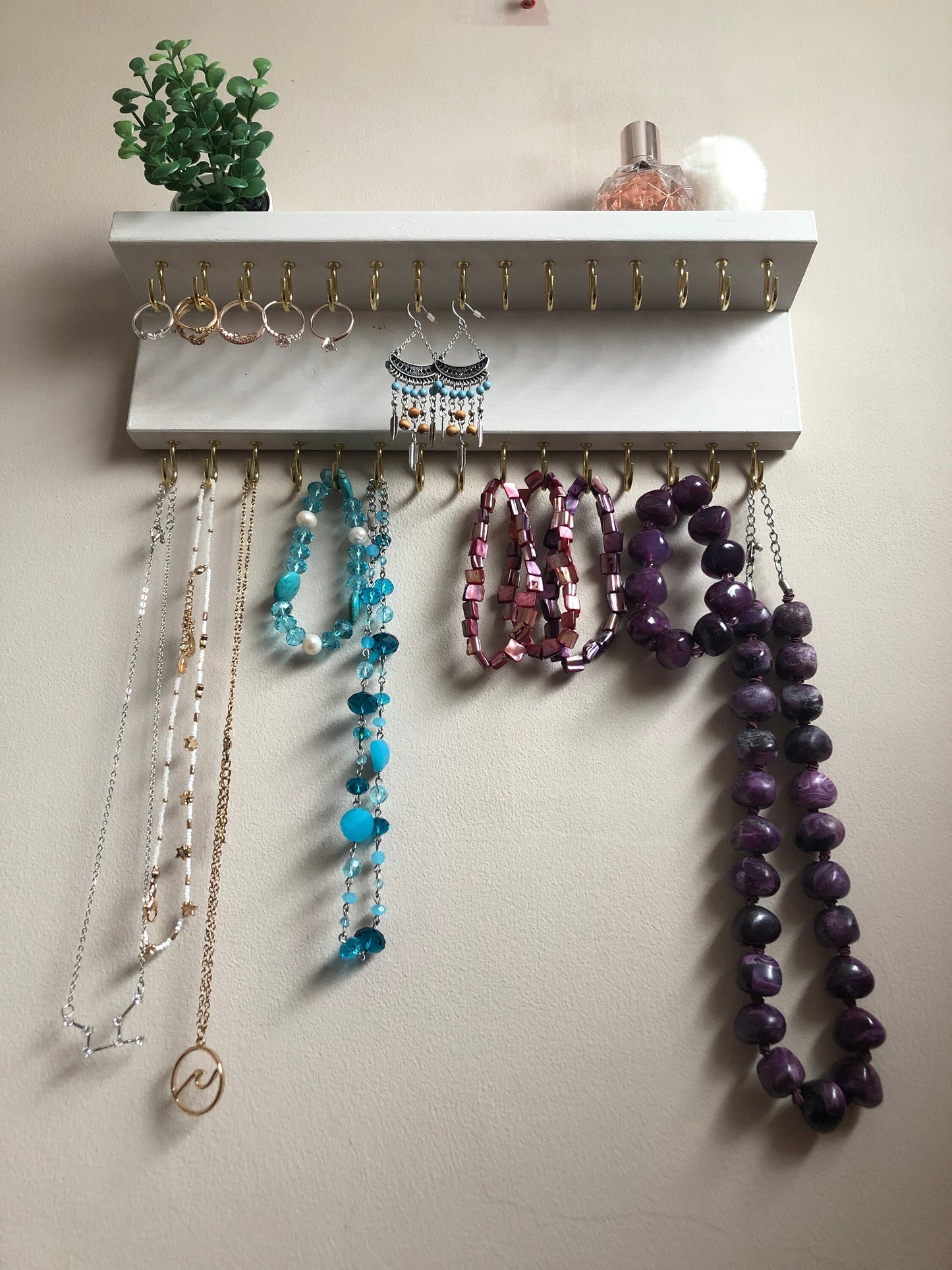 Small style shelf jewellery organiser with two rows of hooks for necklace and jewellry storage. Bottom row of hooks visible beneath the shelf, while another row is discreetly tucked underneath the top ledge. Ideal for keeping your accessories neatly organised and easily accessible.