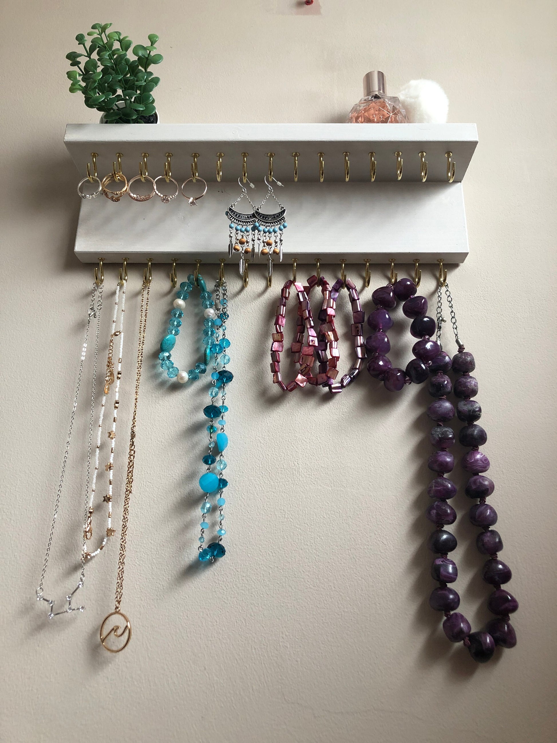 Small style shelf jewellery organiser with two rows of hooks for necklace and jewellry storage. Bottom row of hooks visible beneath the shelf, while another row is discreetly tucked underneath the top ledge. Ideal for keeping your accessories neatly organised and easily accessible.