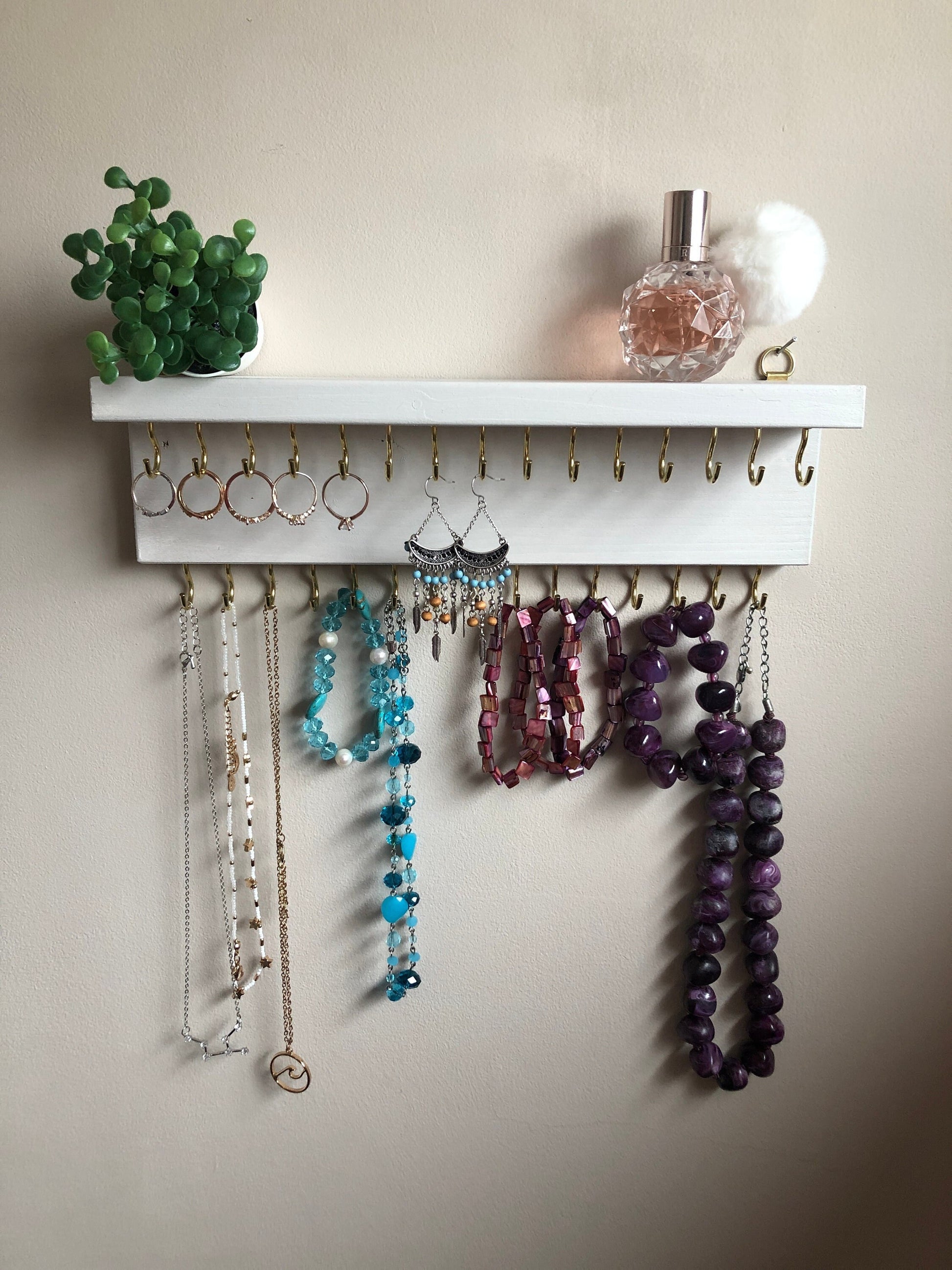 Small style shelf jewellery organiser with two rows of hooks for necklace and jewellry storage. Bottom row of hooks visible beneath the shelf, while another row is discreetly tucked underneath the top ledge. Ideal for keeping your accessories neatly organised and easily accessible.