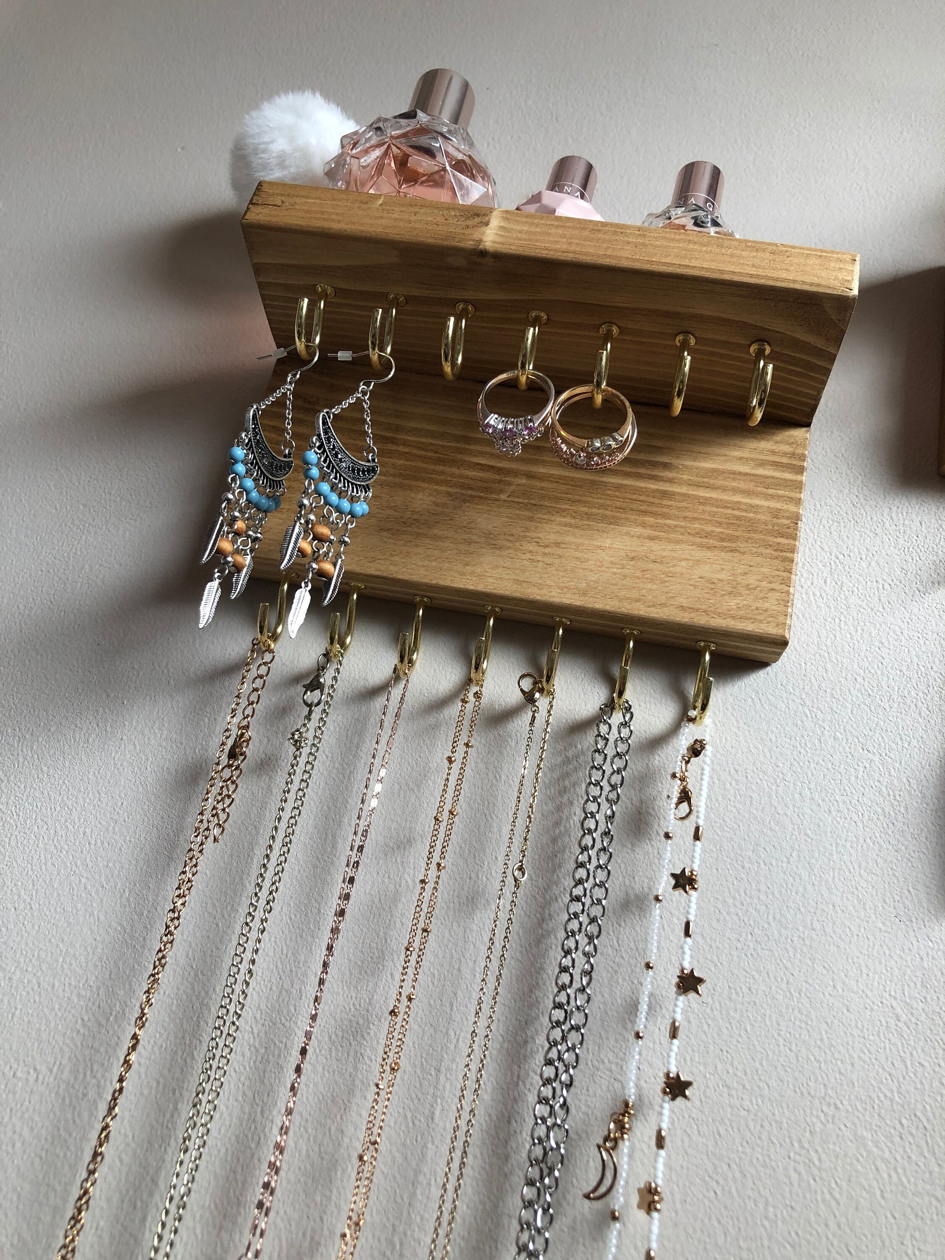 Each organizer, measuring 16cm in length, provides compact storage adaptable to any wall space, boasting a total of 28 hooks for ample room to elegantly display your favorite pieces. Featuring convenient D rings for easy hanging, these organizers double as additional shelving, perfect for storing smaller accessories. Handcrafted from carefully selected timber, each piece exudes natural charm with unique grain patterns, available in enchanting colors like Woodland, Rustic Oak, and Ebony. 