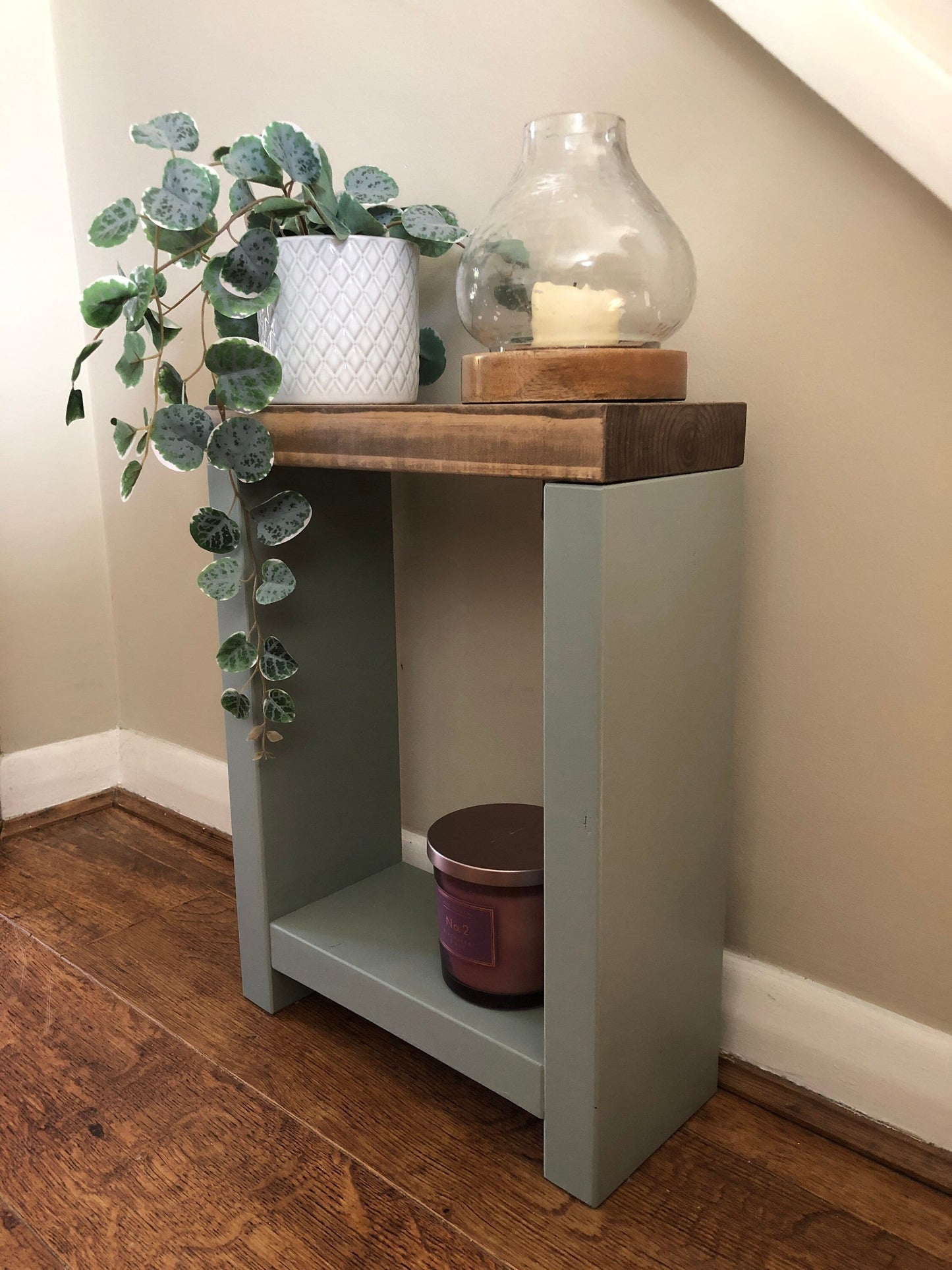 Handmade narrow side table crafted from carefully selected timber, versatile for various settings Features spacious top for plants or candles and low shelf for books or tall vase. Finished with two-tone effect: base in select Farrow and Ball colors, top in Dark Oak or Medium Oak wood dye. Dimensions: H: 44.5cm, W: 33cm, D: 14cm, with 33cm height between shelf and top. Enjoy FREE delivery on all handmade items. Order now for a carefully packaged product crafted with love. Build time: 3-4 weeks.