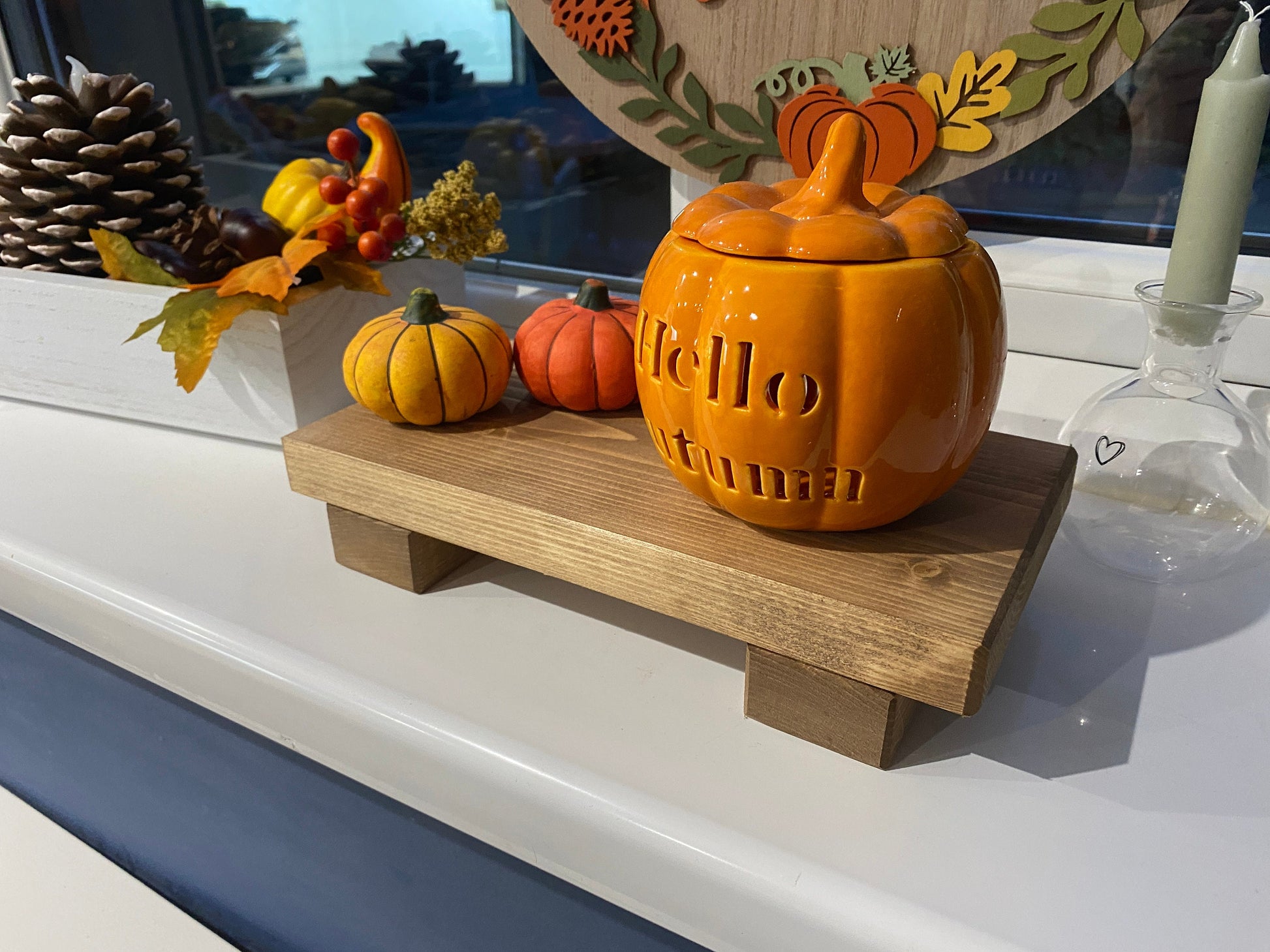 A wooden shelf that stands on two flat wooden legs. It is ideal for placing items on like bottles or candles.