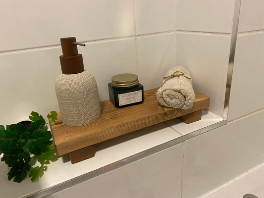 A wooden shelf that stands on two flat wooden legs. It is ideal for placing items on like bottles or candles.