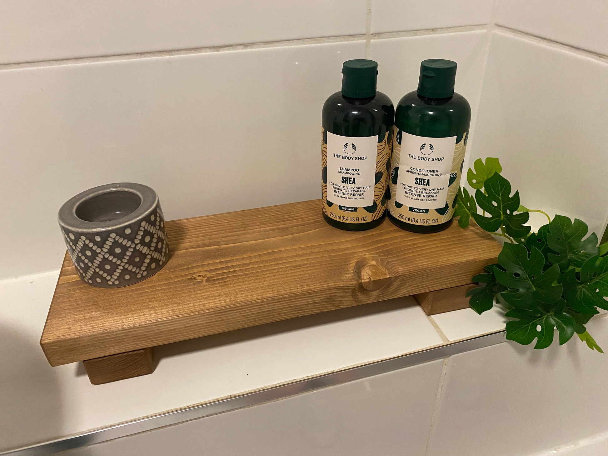 A wooden shelf that stands on two flat wooden legs. It is ideal for placing items on like bottles or candles.